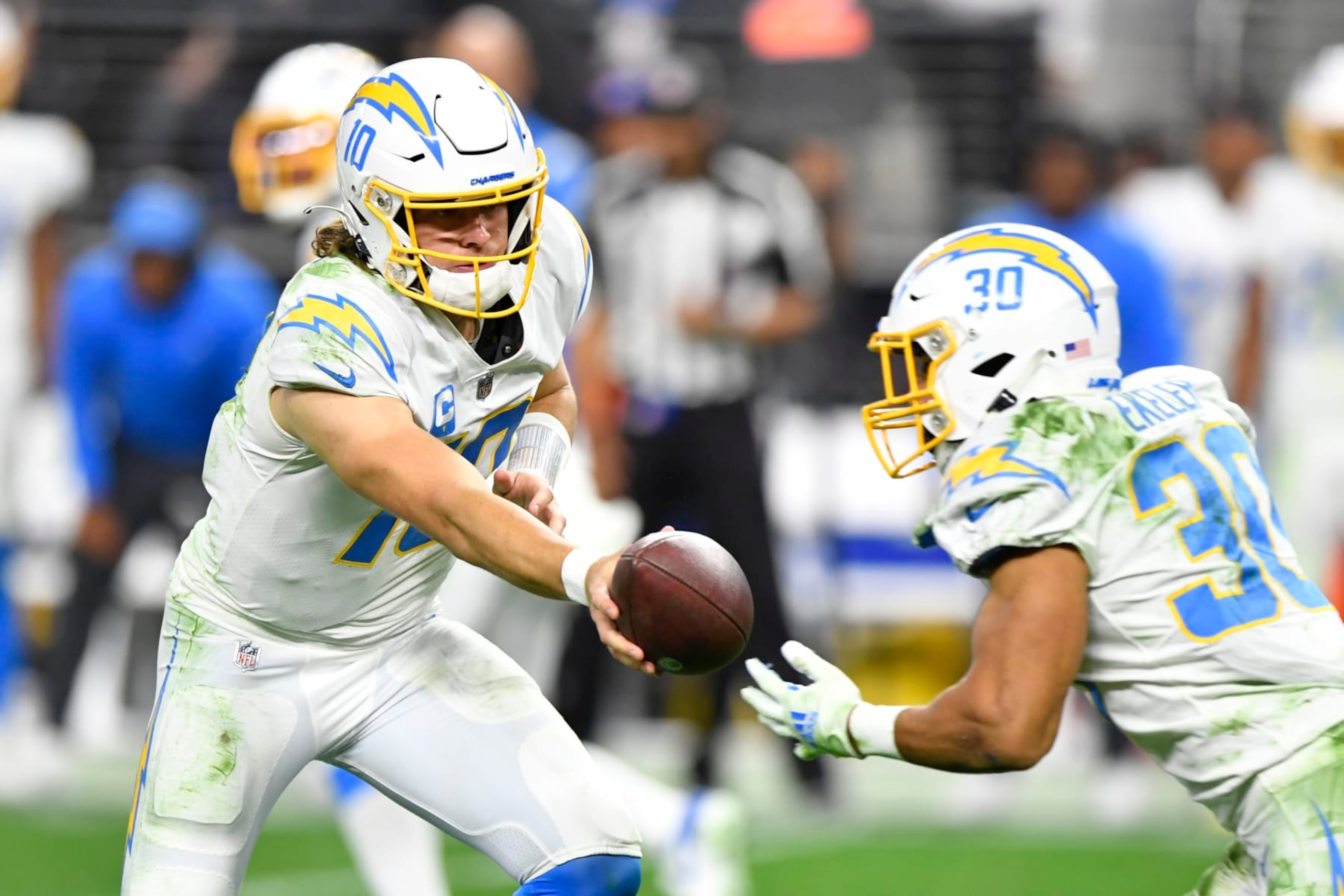 LAS VEGAS, NEVADA - JANUARY 09:  Quarterback Justin Herbert #10 hands the ball off to running back Austin Ekeler #30 of the Los Angeles Chargers during the second half of a game at Allegiant Stadium on January 09, 2022 in Las Vegas, Nevada. The Raiders defeated the Chargers 35-32 in overtime. (Photo by Chris Unger/Getty Images)