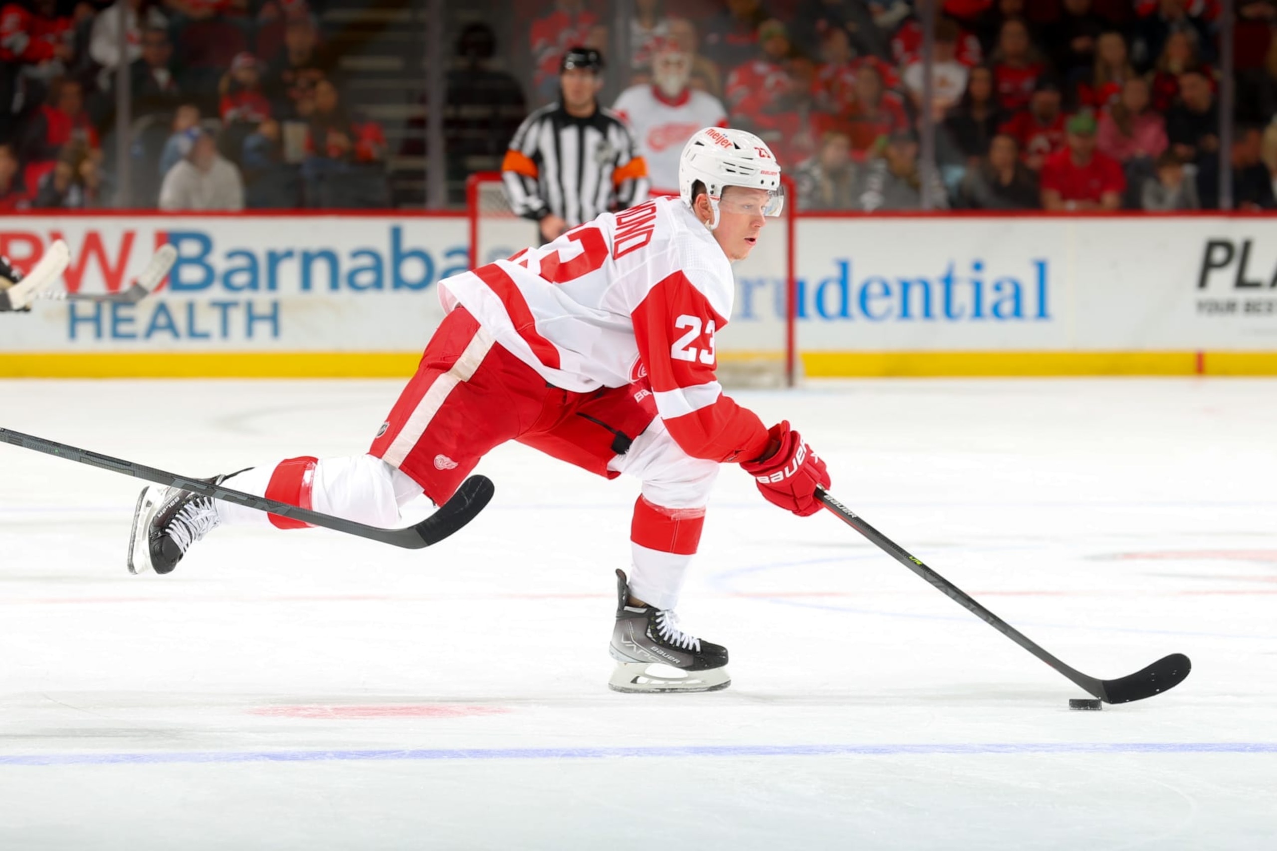 NEWARK, NJ - APRIL  29:   Lucas Raymond #23 of the Detroit Red Wings controls the puck against the New Jersey Devils on April 29, 2022 at the Prudential Center in Newark, New Jersey.  (Photo by Rich Graessle/Getty Images)
