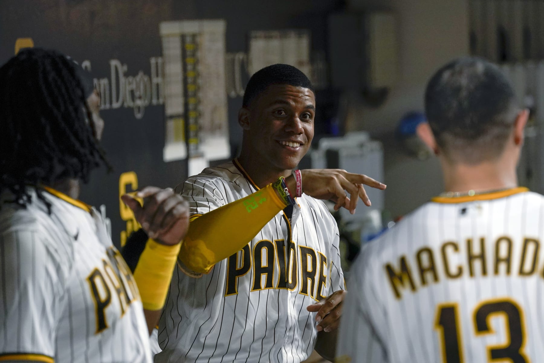 San Diego Padres right fielder Juan Soto, center, jokes with teammates third baseman Manny Machado, right, and first baseman Josh Bell during the fourth inning of the team's baseball game against the Colorado Rockies, Wednesday, Aug. 3, 2022, in San Diego. (AP Photo/Gregory Bull)