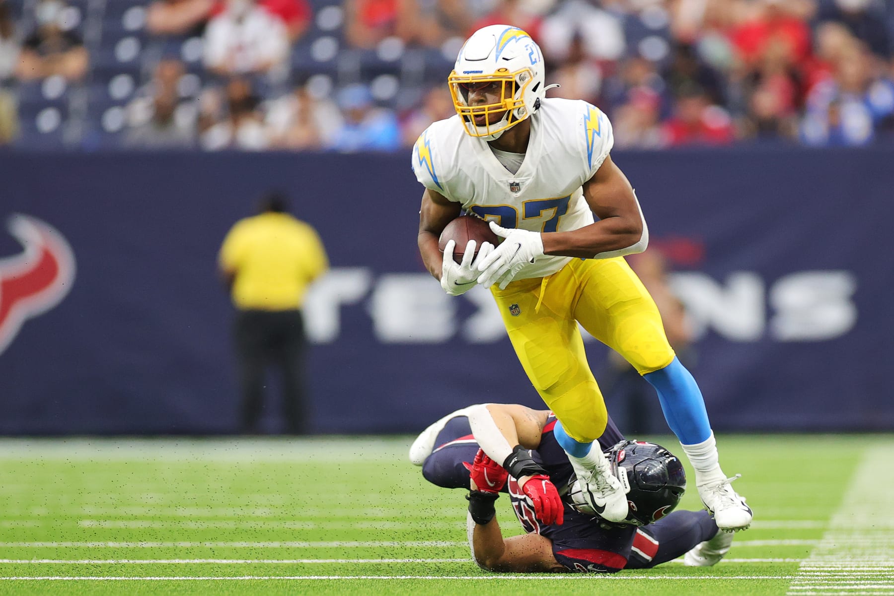 HOUSTON, TEXAS - DECEMBER 26: Joshua Kelley #27 of the Los Angeles Chargers runs the ball ahead of A.J. Moore #33 of the Houston Texans during the third quarter at NRG Stadium on December 26, 2021 in Houston, Texas. (Photo by Carmen Mandato/Getty Images)