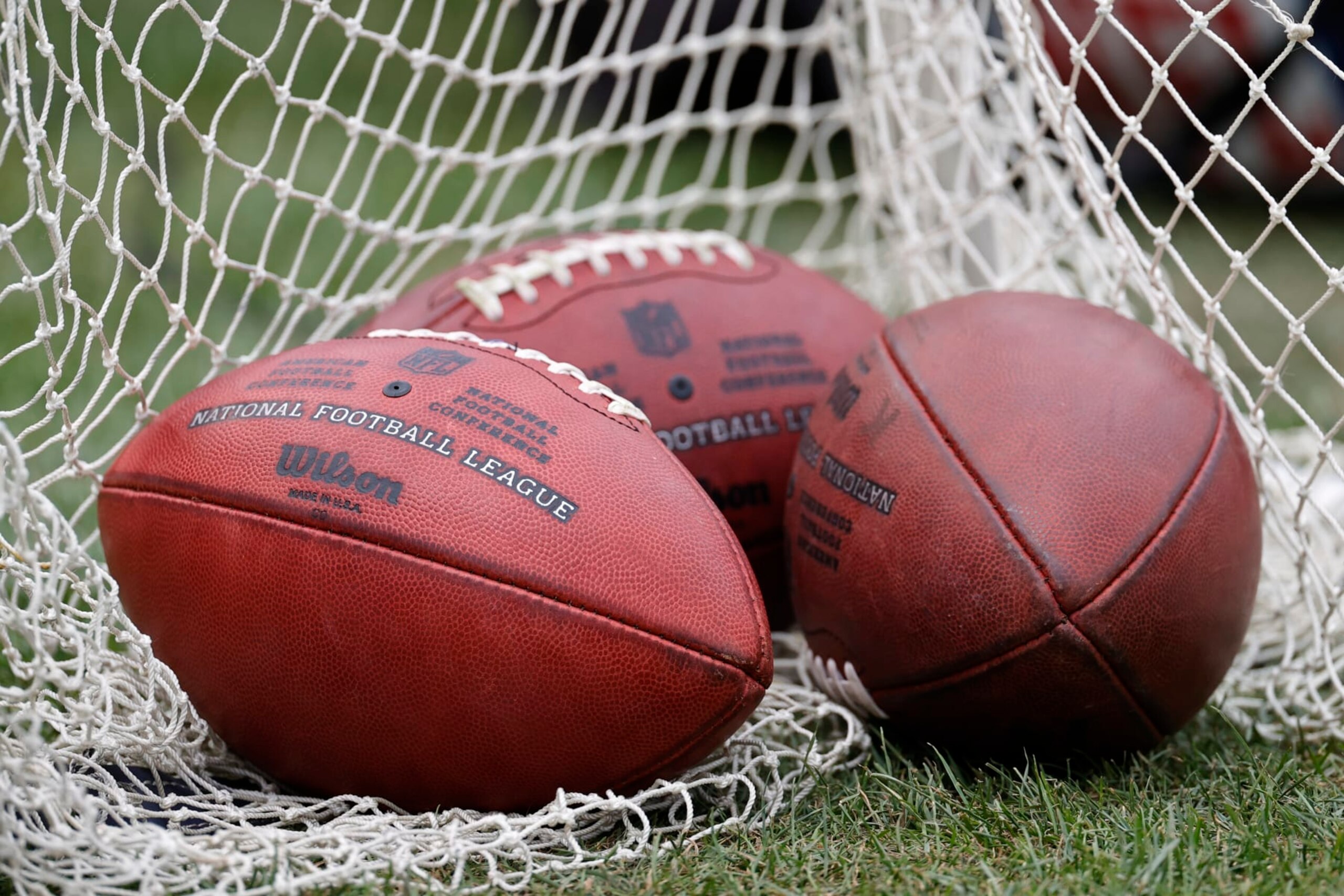 Wilson footballs sit on the sidelines during the first half of a preseason NFL football game between the Chicago Bears and Kansas City Chiefs, Saturday, Aug. 13, 2022, in Chicago. (AP Photo/Kamil Krzaczynski)