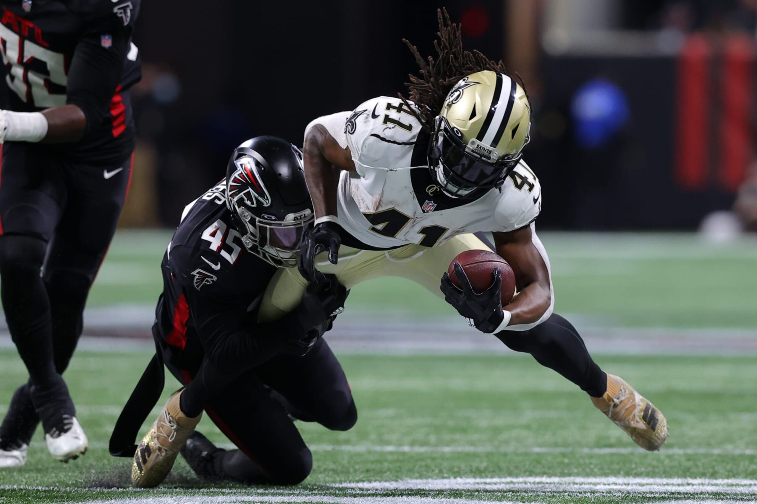 ATLANTA, GEORGIA - JANUARY 09: Alvin Kamara #41 of the New Orleans Saints is tackled by Deion Jones #45 of the Atlanta Falcons during the second quarter at Mercedes-Benz Stadium on January 09, 2022 in Atlanta, Georgia. (Photo by Todd Kirkland/Getty Images)