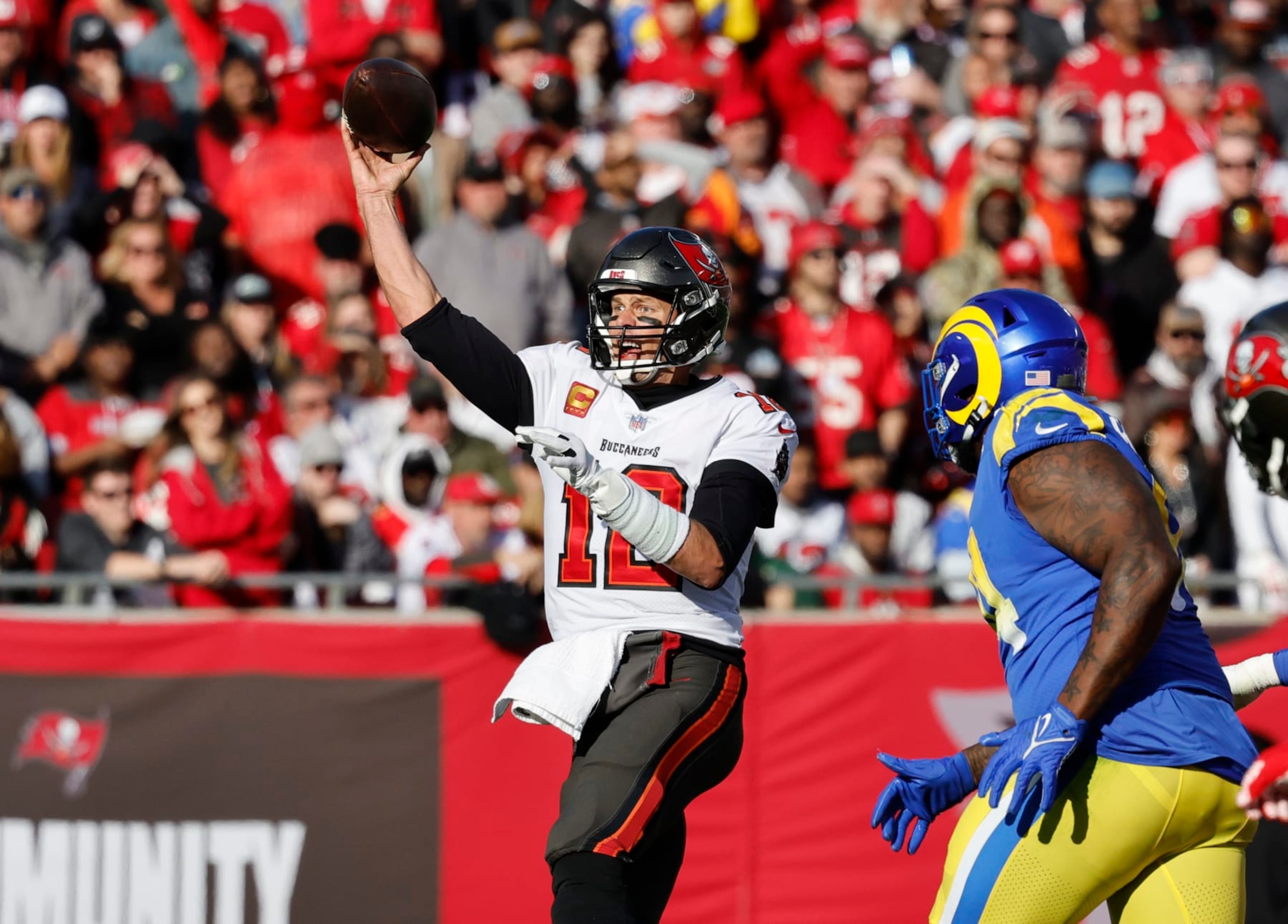 TAMPA BAY, FL- JANUARY 23, 2022: Tampa Bay Buccaneers quarterback Tom Brady (12) makes a pass against Los Angeles Rams defensive end A'Shawn Robinson (94)  in the NFC Divisional game at Raymond James Stadium on January 23, 2022 in Tampa Bay, Florida. He announced today that he is retiring after 22 years in the NFL.(Gina Ferazzi / Los Angeles Times via Getty Images)