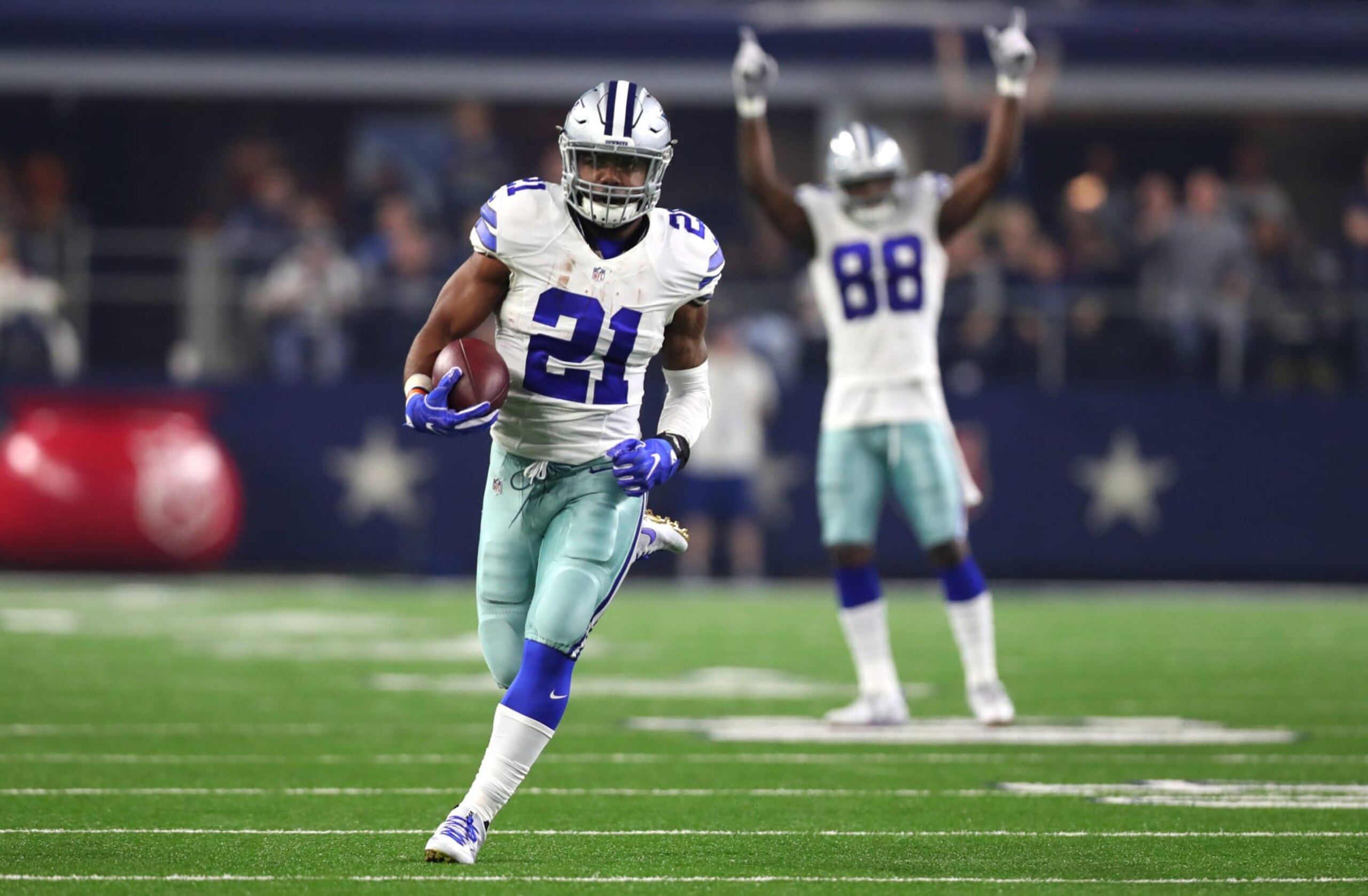 ARLINGTON, TX - DECEMBER 26: Ezekiel Elliott #21 of the Dallas Cowboys runs for a touchdown as teammate Dez Bryant #88 celebrates as the Cowboys play the Detroit Lions during the first half at AT&T Stadium on December 26, 2016 in Arlington, Texas. (Photo by Tom Pennington/Getty Images)