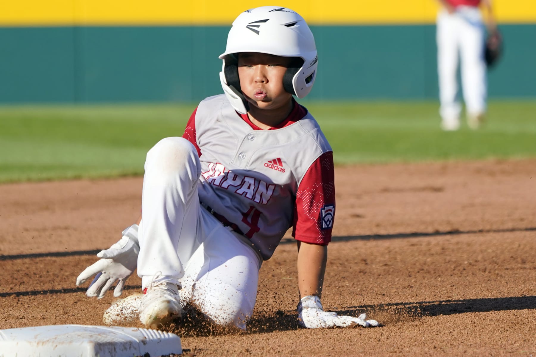 Japan's Halu Kunimitsu (4) slides into third base against Canada during the fourth inning of a baseball game at the Little League World Series tournament in South Williamsport, Pa., Friday, Aug. 19, 2022. Canada won the game 6-0. (AP Photo/Tom E. Puskar)