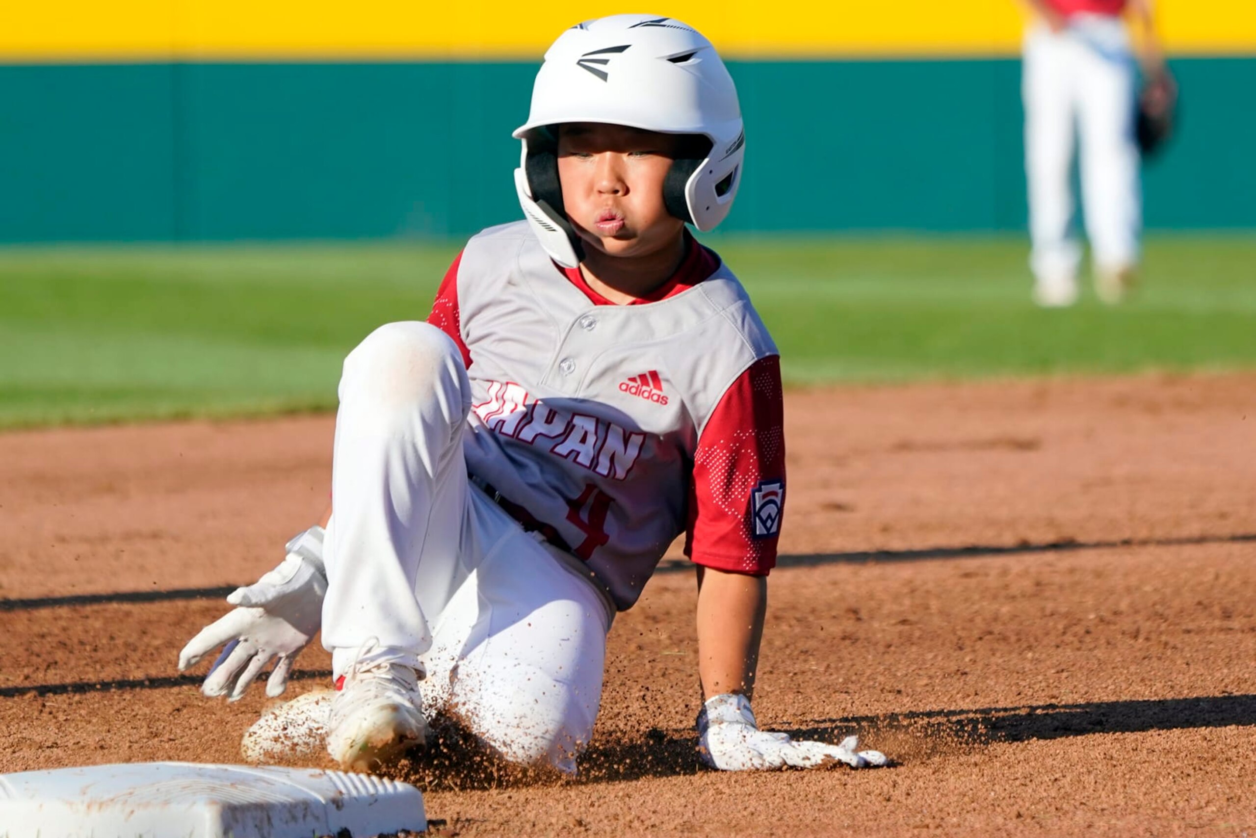 Japan's Halu Kunimitsu (4) slides into third base against Canada during the fourth inning of a baseball game at the Little League World Series tournament in South Williamsport, Pa., Friday, Aug. 19, 2022. Canada won the game 6-0. (AP Photo/Tom E. Puskar)