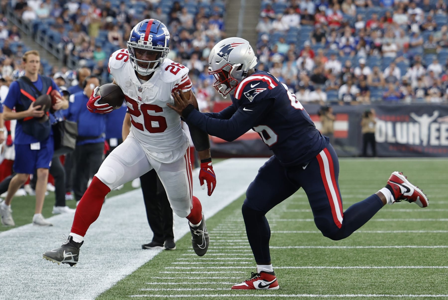 FOXBOROUGH, MA - AUGUST 11: New York Giants running back Saquon Barkley (26) pushed out of bounds by New England Patriots cornerback Shaun Wade (26) during an NFL preseason game between the New England Patriots and the New York Giants on August 11, 2022, at Gillette Stadium in Foxborough, Massachusetts. (Photo by Fred Kfoury III/Icon Sportswire via Getty Images)
