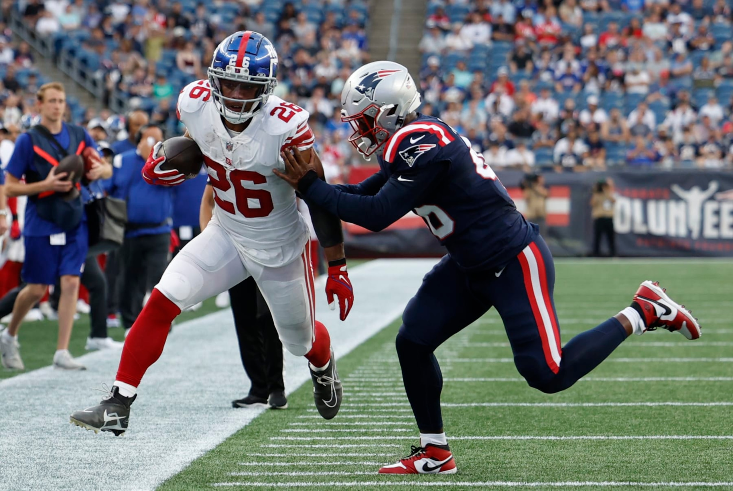 FOXBOROUGH, MA - AUGUST 11: New York Giants running back Saquon Barkley (26) pushed out of bounds by New England Patriots cornerback Shaun Wade (26) during an NFL preseason game between the New England Patriots and the New York Giants on August 11, 2022, at Gillette Stadium in Foxborough, Massachusetts. (Photo by Fred Kfoury III/Icon Sportswire via Getty Images)