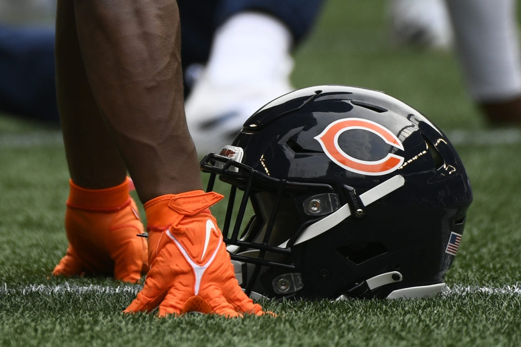 A Chicago Bears helmet rests on the turf as players stretch before a preseason NFL football game against the Seattle Seahawks, Thursday, Aug. 18, 2022, in Seattle. (AP Photo/Caean Couto)