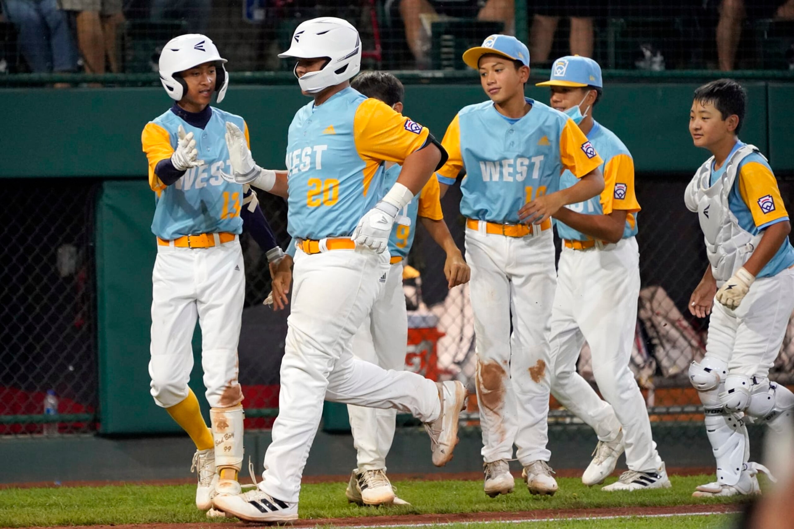 Honolulu's Esaiah Wong (20) is greeted by his teammate along the third base line as he heads home on his home run off of Massapequa, N.Y.'s Lucas Mininni during the fifth inning of a baseball game at the Little League World Series in South Williamsport, Pa., Friday, Aug. 19, 2022. (AP Photo/Tom E. Puskar)