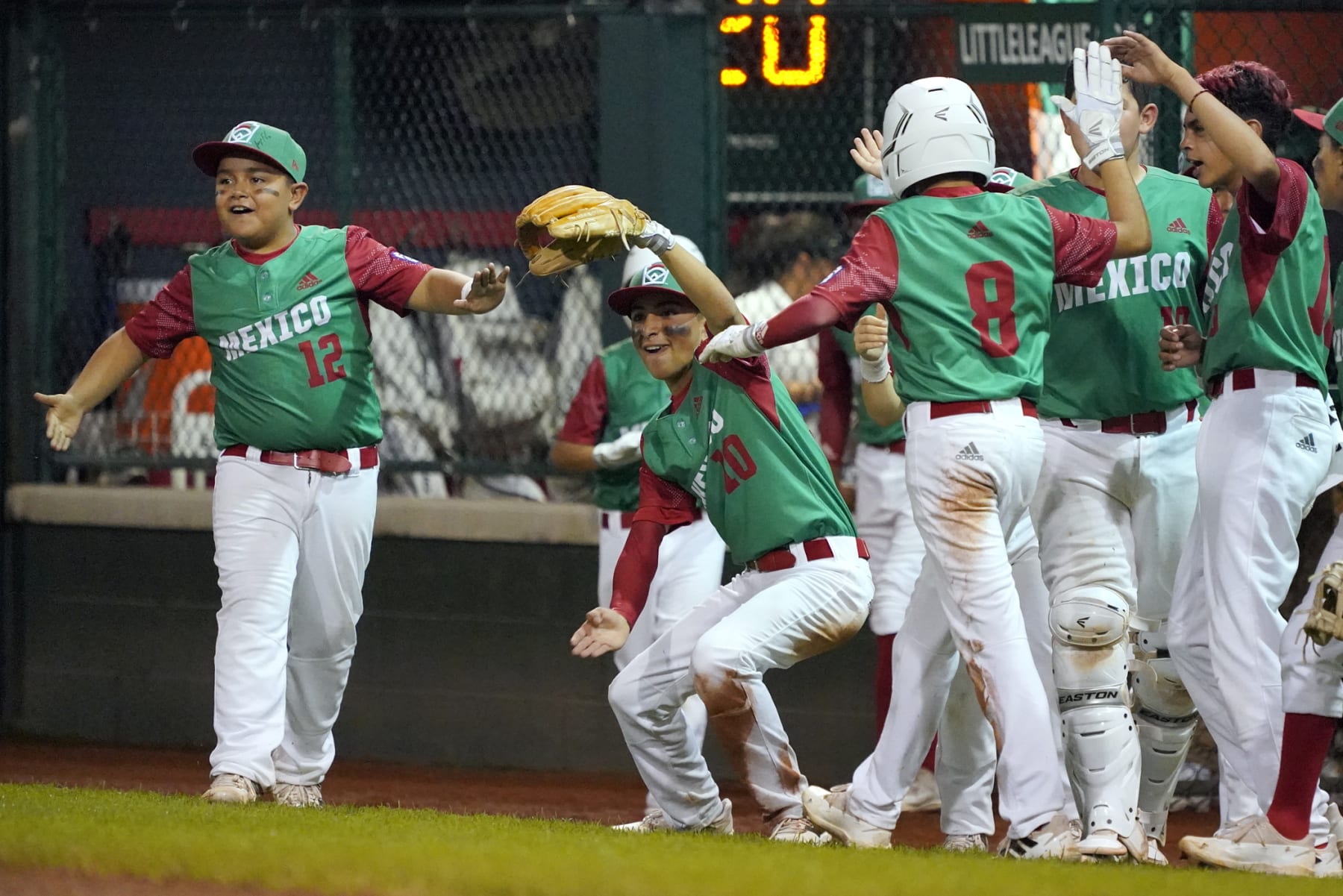 Mexico's Marco Covarrubias (8) is greeted by his teammates on his way back to the dugout after scoring on a double by Juan Pablo Puente against Canada during the second inning of a baseball game at the Little League World Series tournament in South Williamsport, Pa., Monday, Aug. 22, 2022. (AP Photo/Tom E. Puskar)