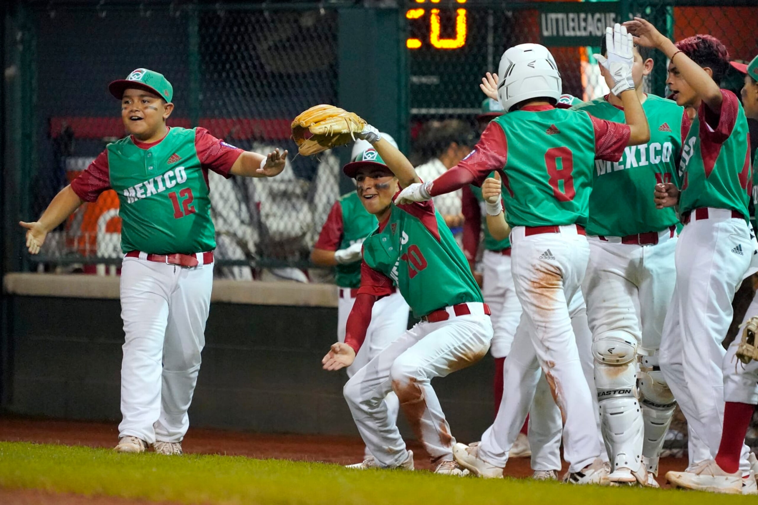 Mexico's Marco Covarrubias (8) is greeted by his teammates on his way back to the dugout after scoring on a double by Juan Pablo Puente against Canada during the second inning of a baseball game at the Little League World Series tournament in South Williamsport, Pa., Monday, Aug. 22, 2022. (AP Photo/Tom E. Puskar)