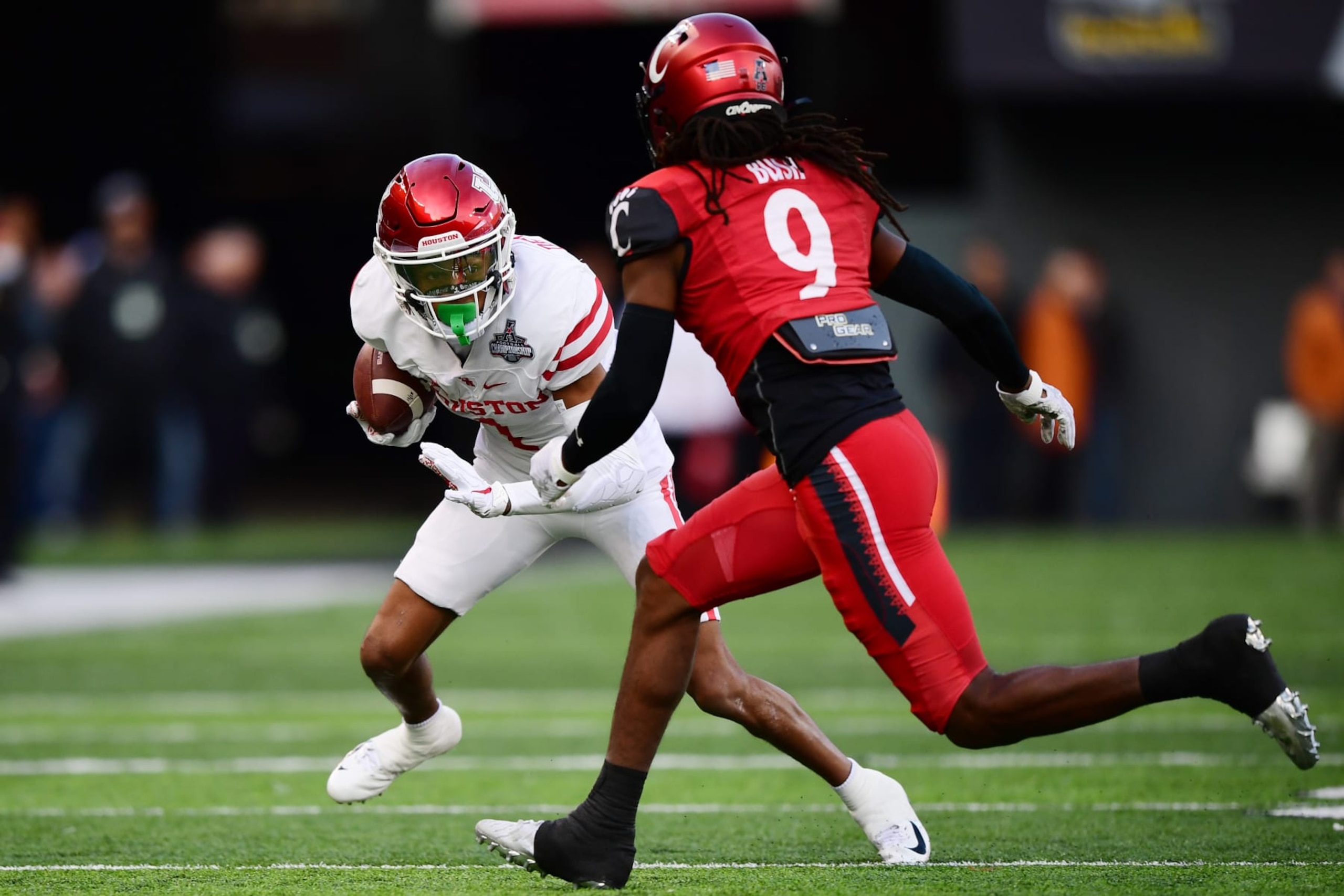 CINCINNATI, OHIO - DECEMBER 04: Nathaniel Dell #1 of the Houston Cougars carries the ball against Arquon Bush #9 of the Cincinnati Bearcats during the first half of the 2021 American Conference Championship at Nippert Stadium on December 04, 2021 in Cincinnati, Ohio. (Photo by Emilee Chinn/Getty Images)