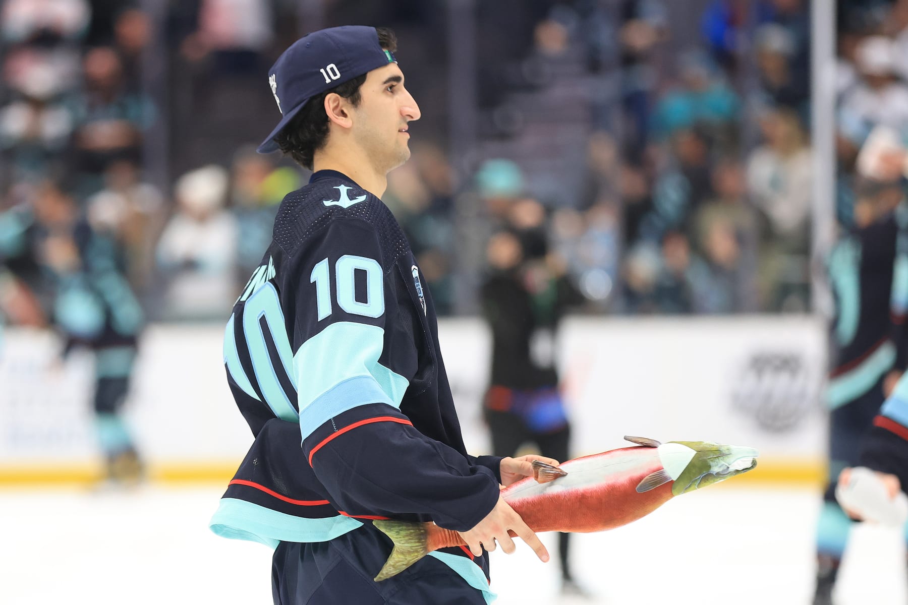 SEATTLE, WASHINGTON - APRIL 29: Matty Beniers #10 of the Seattle Kraken looks to throw a stuffed salmon to fans as a part of Fan Appreciation Night following the 3-0 win against the San Jose Sharks at Climate Pledge Arena on April 29, 2022 in Seattle, Washington. (Photo by Abbie Parr/2022 NHLI via Getty Images)