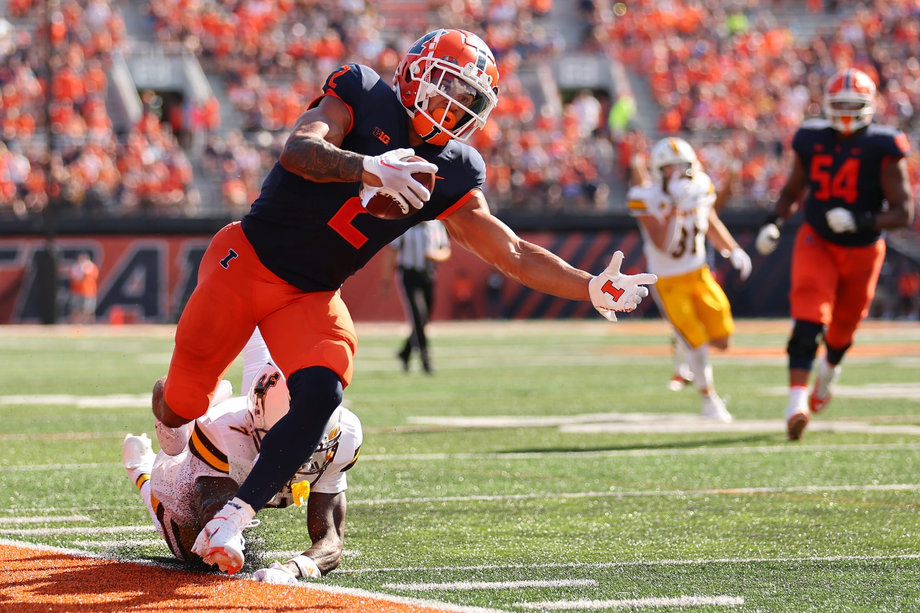CHAMPAIGN, ILLINOIS - AUGUST 27: Chase Brown #2 of the Illinois Fighting Illini is tackled out of bounds by Jakorey Hawkins #7 of the Wyoming Cowboys during the first half at Memorial Stadium on August 27, 2022 in Champaign, Illinois. (Photo by Michael Reaves/Getty Images)