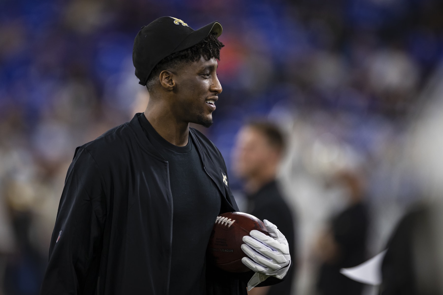 BALTIMORE, MD - AUGUST 14: Michael Thomas #13 of the New Orleans Saints hold a football on the sidelines while wearing receiver gloves in street clothes during the second half of a preseason game against the Baltimore Ravens at M&T Bank Stadium on August 14, 2021 in Baltimore, Maryland. (Photo by Scott Taetsch/Getty Images)