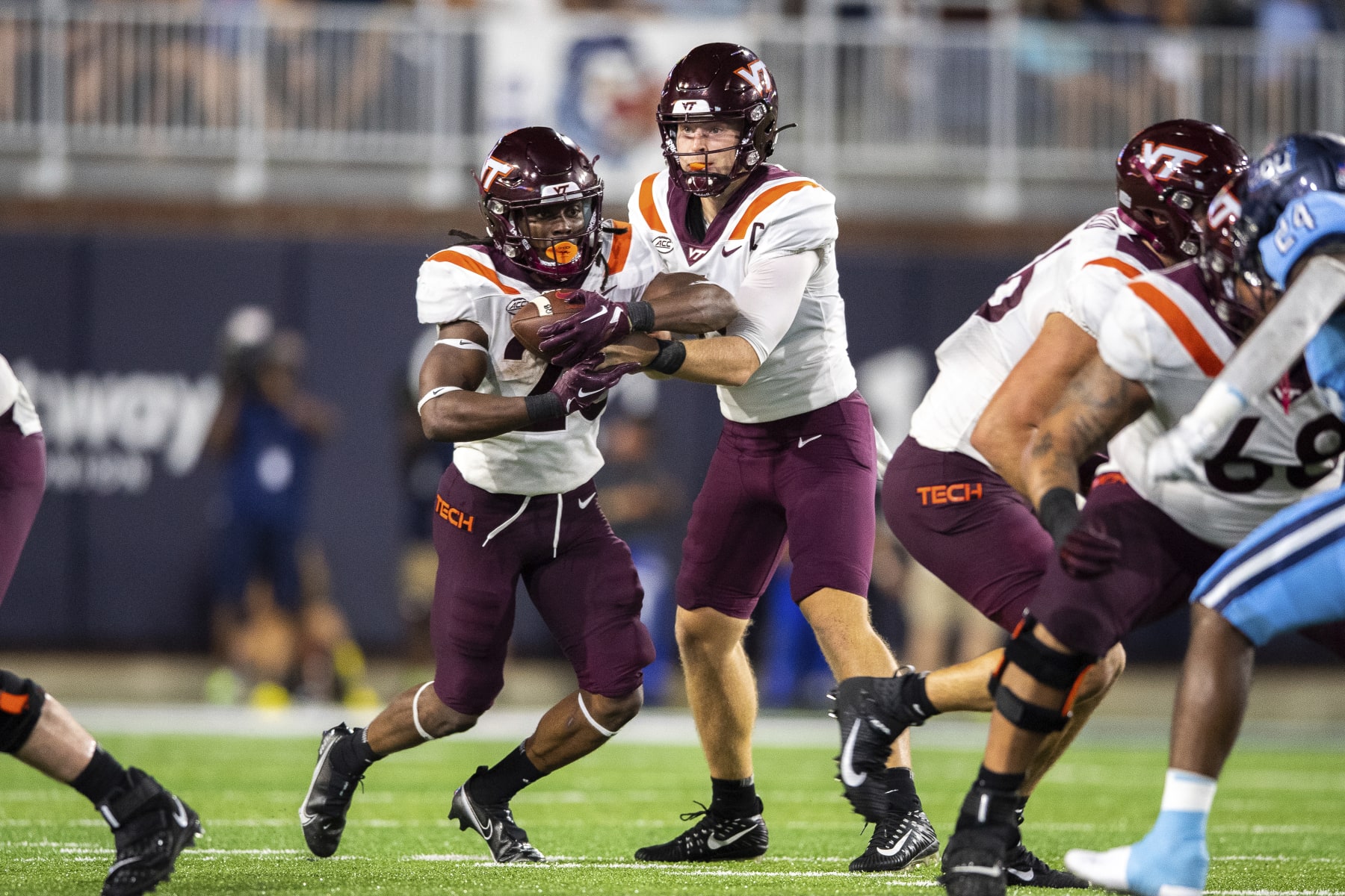 Virginia Tech quarterback Grant Wells, center right, hands off the ball to running back Keshawn King, center left, during the first half of an NCAA college football game on Friday, Sept. 2, 2022, in Norfolk, Va. (AP Photo/Mike Caudill)