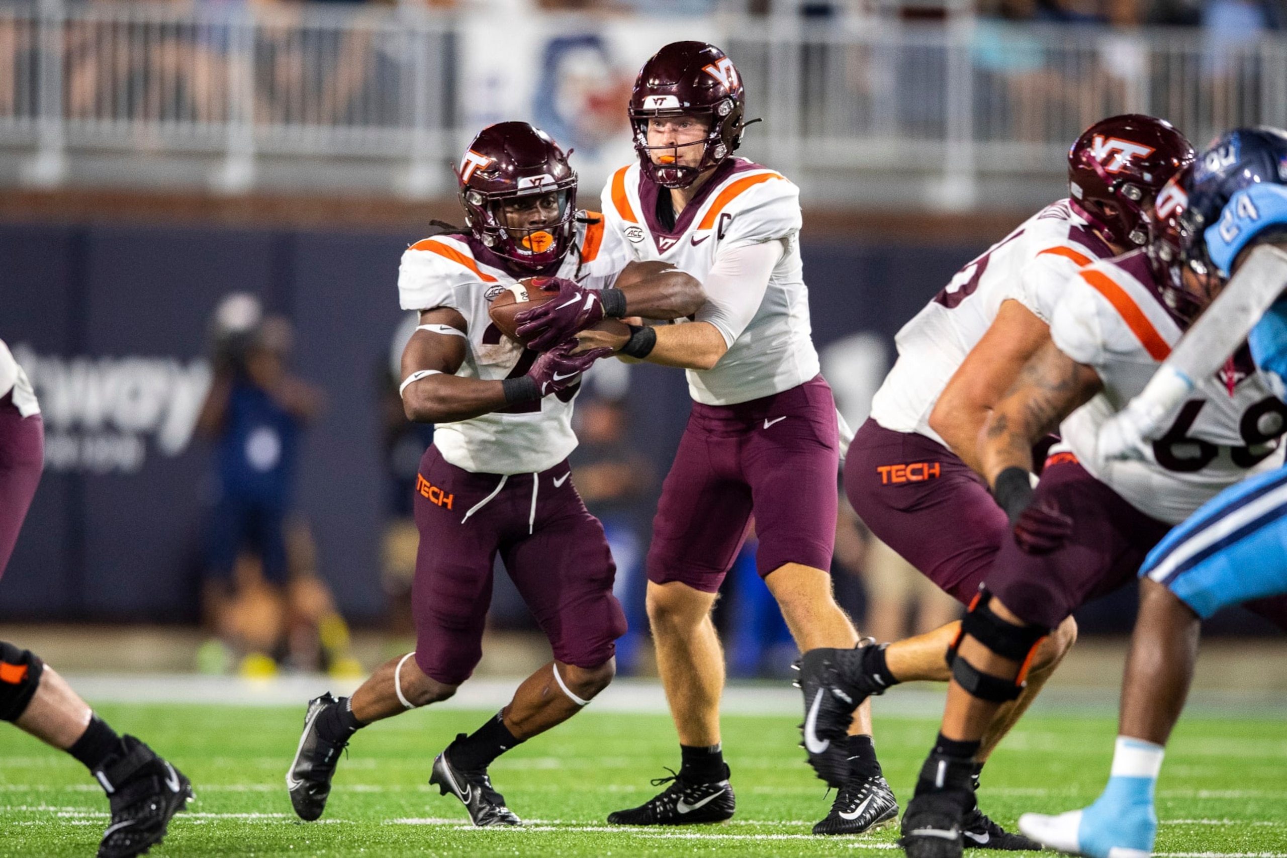 Virginia Tech quarterback Grant Wells, center right, hands off the ball to running back Keshawn King, center left, during the first half of an NCAA college football game on Friday, Sept. 2, 2022, in Norfolk, Va. (AP Photo/Mike Caudill)