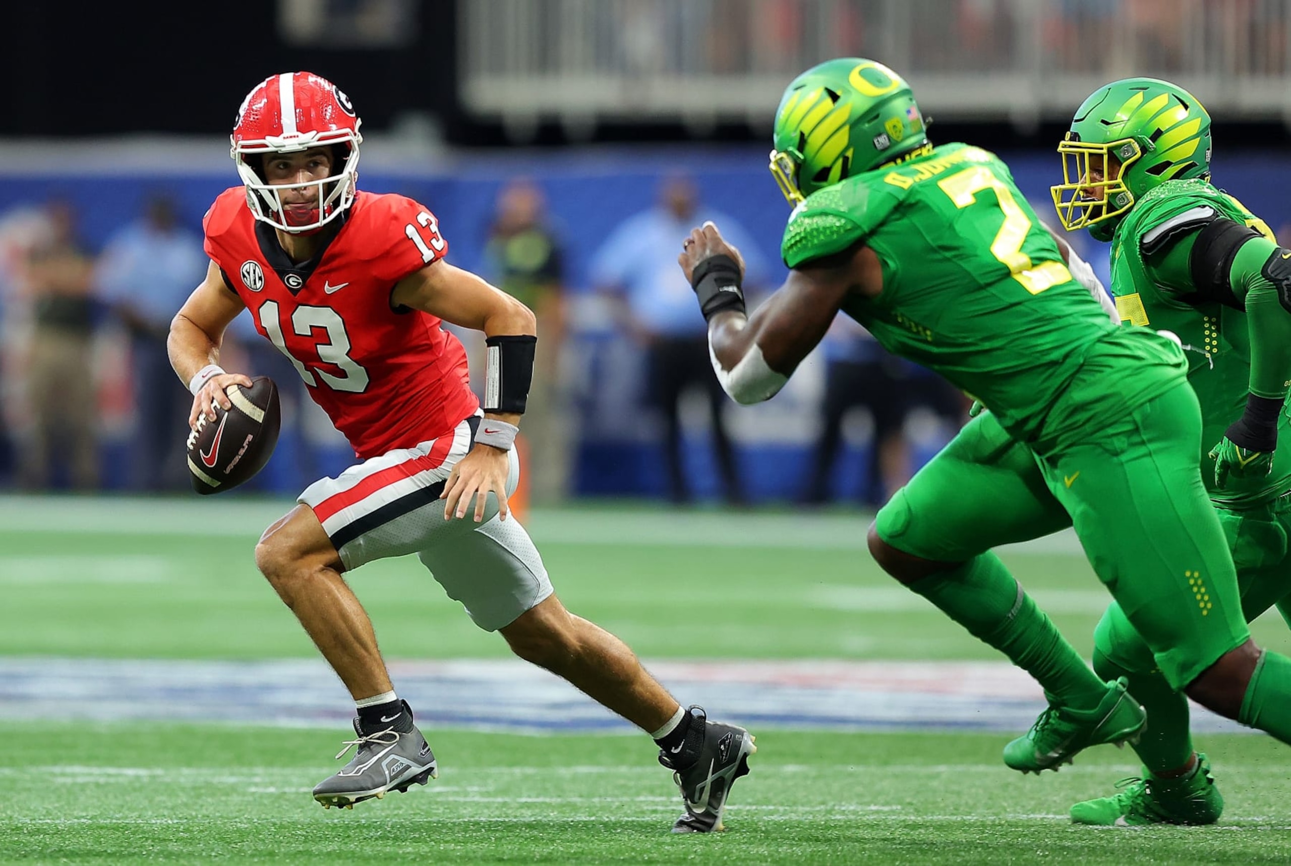 ATLANTA, GEORGIA - SEPTEMBER 03:  Stetson Bennett #13 of the Georgia Bulldogs escapes the pocket away from DJ Johnson #2 and Keyon Ware-Hudson #95 of the Oregon Ducks in the first quarter of the Chick-fil-A Kick-Off Game at Mercedes-Benz Stadium on September 03, 2022 in Atlanta, Georgia. (Photo by Kevin C. Cox/Getty Images)