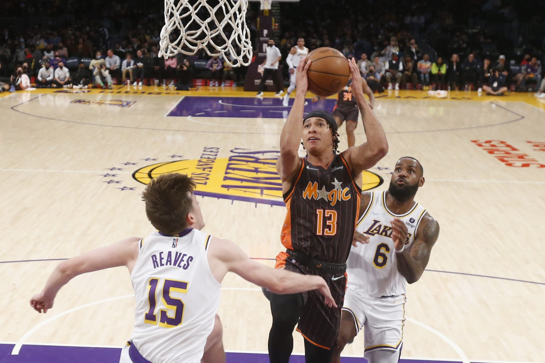 Orlando Magic guard R.J. Hampton (13) drives to basket between Los Angeles Lakers guard Austin Reaves (15) and forward LeBron James (6) during the first half of an NBA basketball game in Los Angeles, Sunday, Dec. 12, 2021. (AP Photo/Ringo H.W. Chiu)