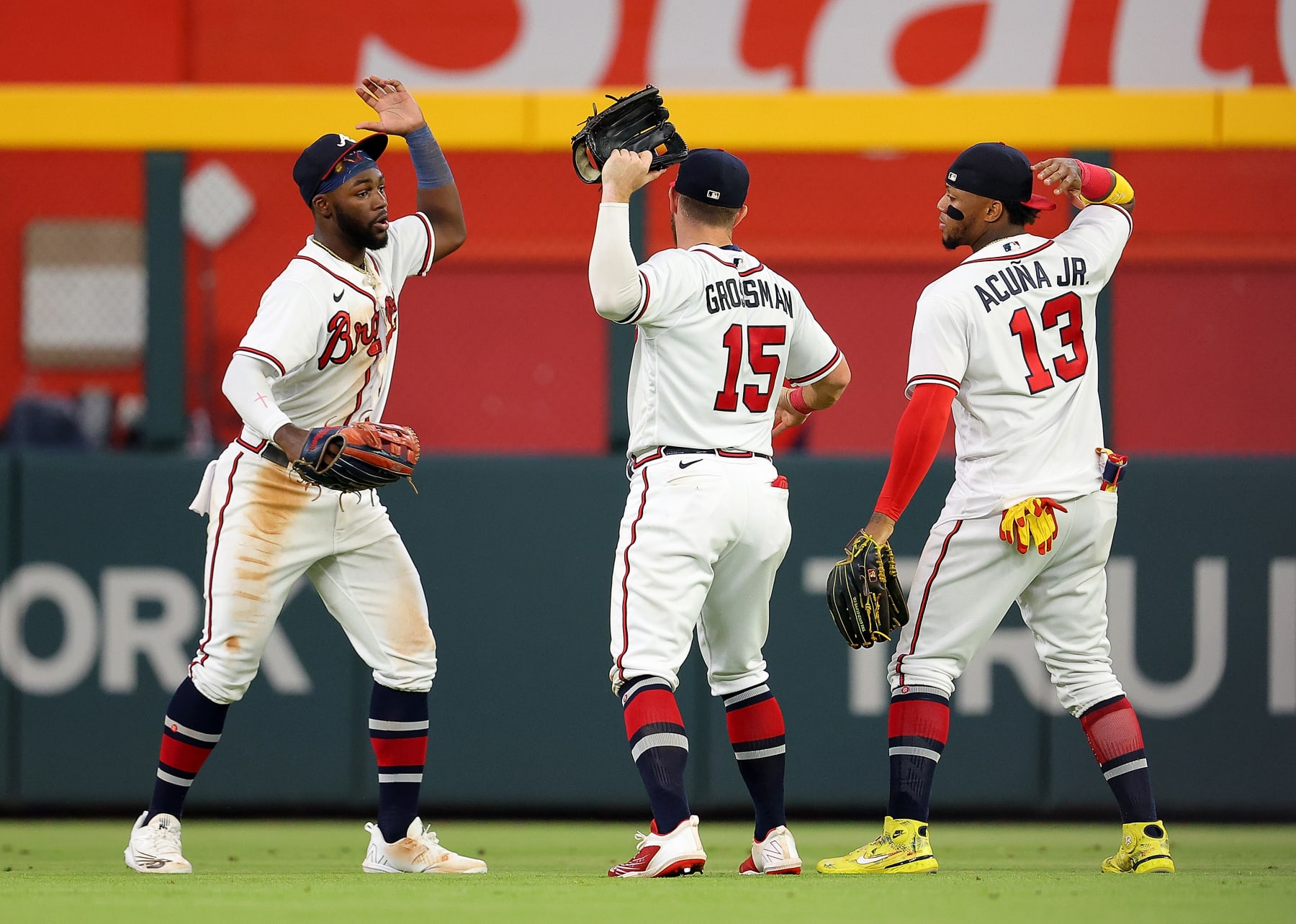 ATLANTA, GEORGIA - AUGUST 18:  Michael Harris II #23, Robbie Grossman #15, and Ronald Acuna Jr. #13 of the Atlanta Braves react after their 3-2 win over the New York Mets at Truist Park on August 18, 2022 in Atlanta, Georgia. (Photo by Kevin C. Cox/Getty Images)