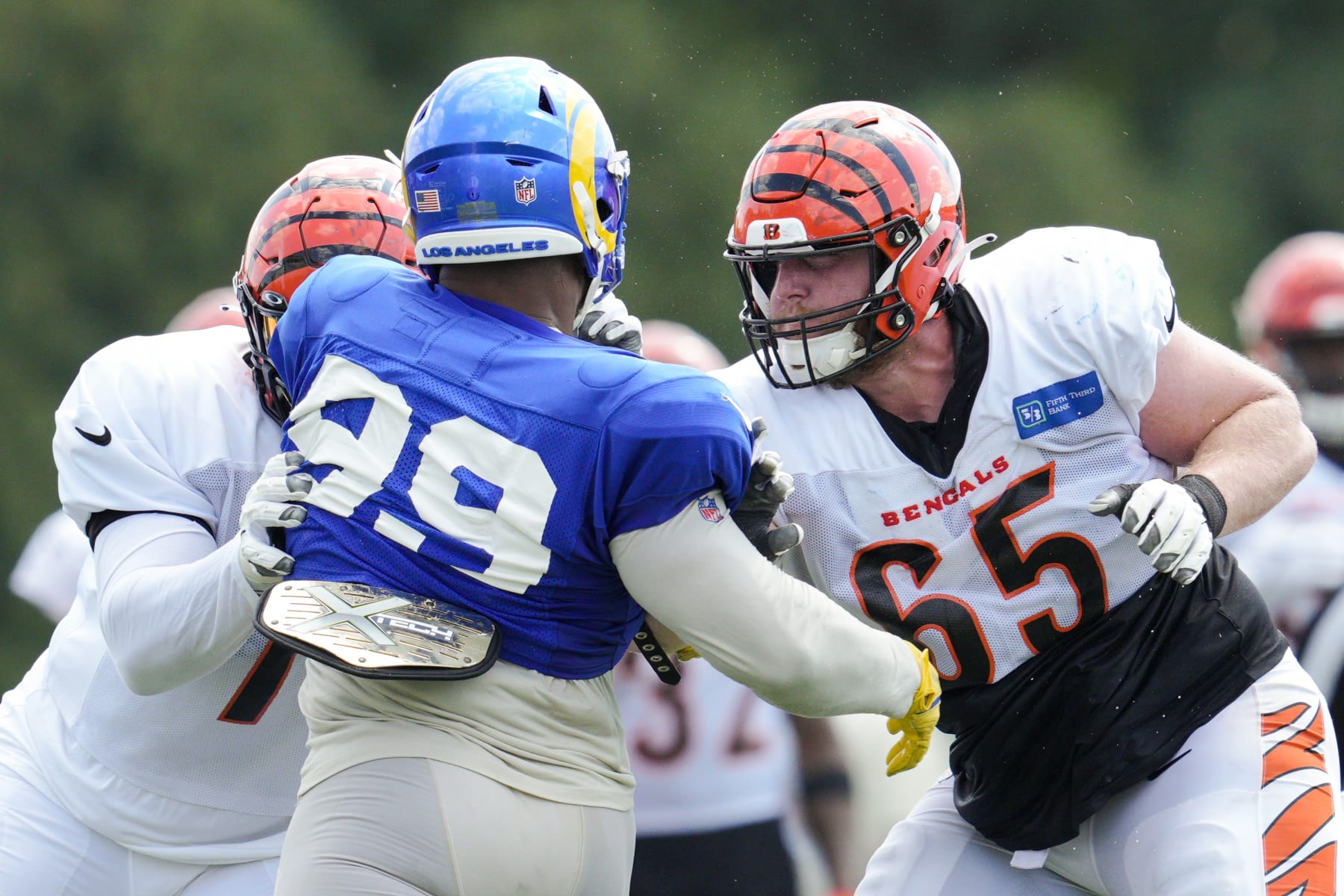 Cincinnati Bengals guard Alex Cappa (65) and offensive tackle La'el Collins, left, block Los Angeles Rams defensive tackle Aaron Donald (99) during a drill at the team's NFL football training facility, Wednesday, Aug. 24, 2022, in Cincinnati. (AP Photo/Jeff Dean)