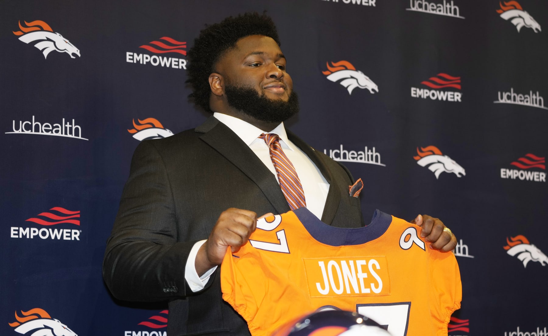 New Denver Broncos defensive tackle D.J. Jones holds up a jersey during an NFL football news conference Thursday, March 17, 2022, at the team's headquarters in Englewood, Colo. (AP Photo/David Zalubowski)