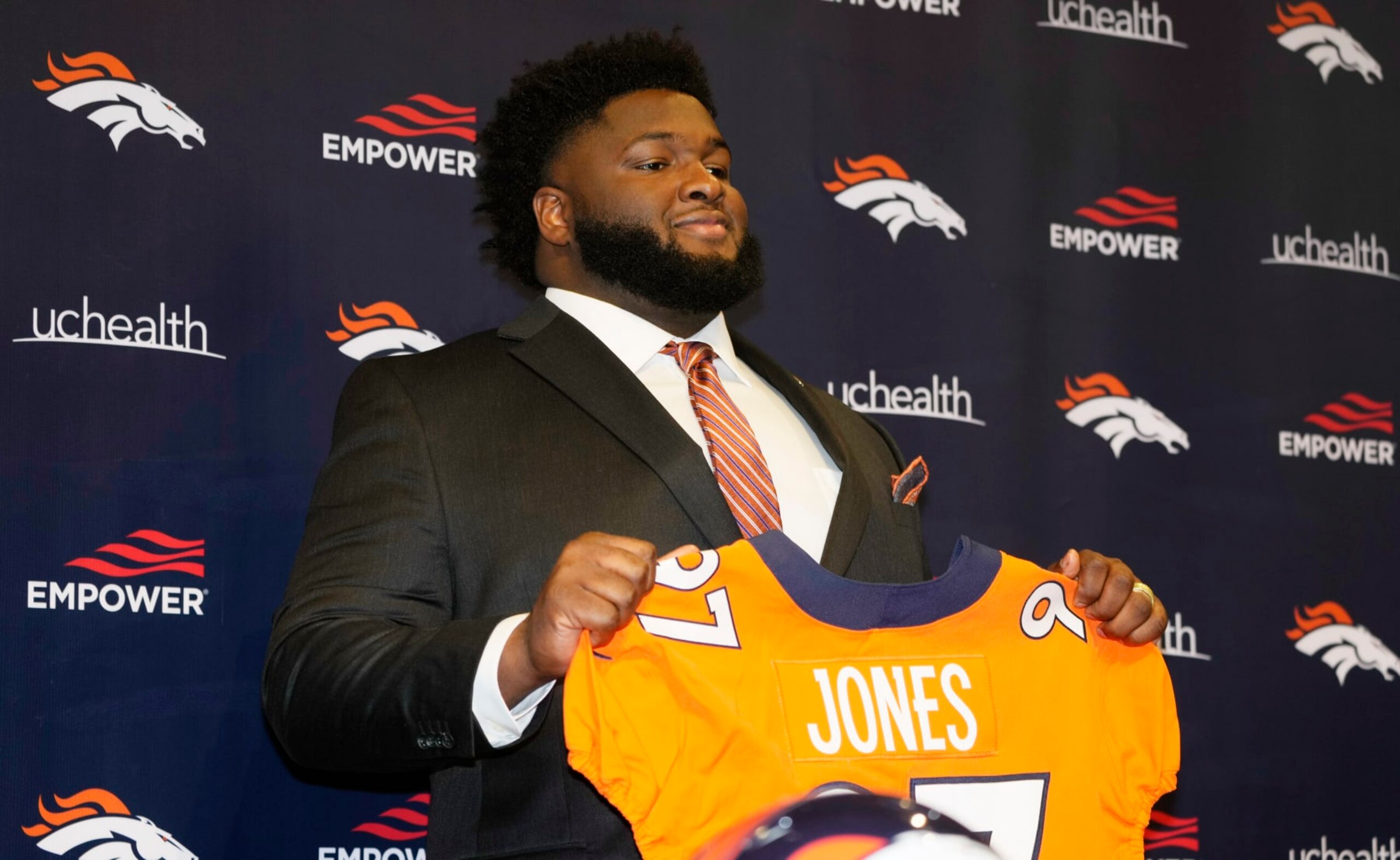 New Denver Broncos defensive tackle D.J. Jones holds up a jersey during an NFL football news conference Thursday, March 17, 2022, at the team's headquarters in Englewood, Colo. (AP Photo/David Zalubowski)