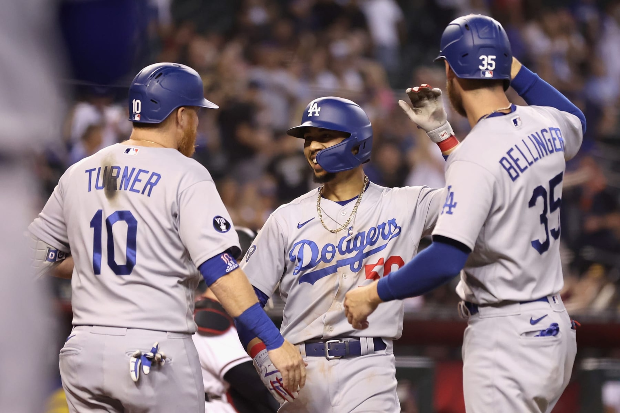PHOENIX, ARIZONA - SEPTEMBER 12:  Mookie Betts #50 of the Los Angeles Dodgers high fives Justin Turner #10 and Cody Bellinger #35 after hitting a three-run home run against the Arizona Diamondbacks during the ninth inning of the MLB game at Chase Field on September 12, 2022 in Phoenix, Arizona. The Dodgers defeated the Diamondbacks 6-0.  (Photo by Christian Petersen/Getty Images)