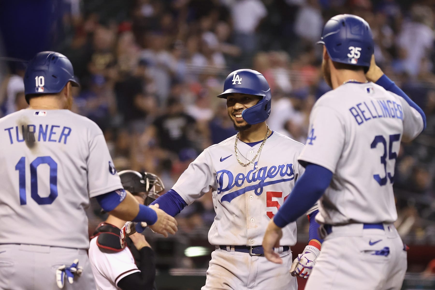 PHOENIX, ARIZONA - SEPTEMBER 12:  Mookie Betts #50 of the Los Angeles Dodgers high fives Justin Turner #10 and Cody Bellinger #35 after hitting a three-run home run against the Arizona Diamondbacks during the ninth inning of the MLB game at Chase Field on September 12, 2022 in Phoenix, Arizona. The Dodgers defeated the Diamondbacks 6-0.  (Photo by Christian Petersen/Getty Images)