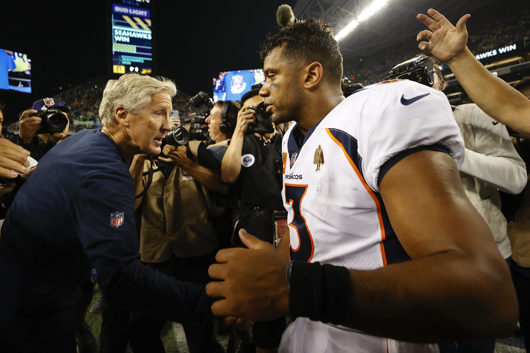 SEATTLE, WASHINGTON - SEPTEMBER 12: Head coach Pete Carroll of the Seattle Seahawks (L) and Russell Wilson #3 of the Denver Broncos shake hands after the Seahawks defeated the Broncos 17-16 at Lumen Field on September 12, 2022 in Seattle, Washington. (Photo by Steph Chambers/Getty Images)