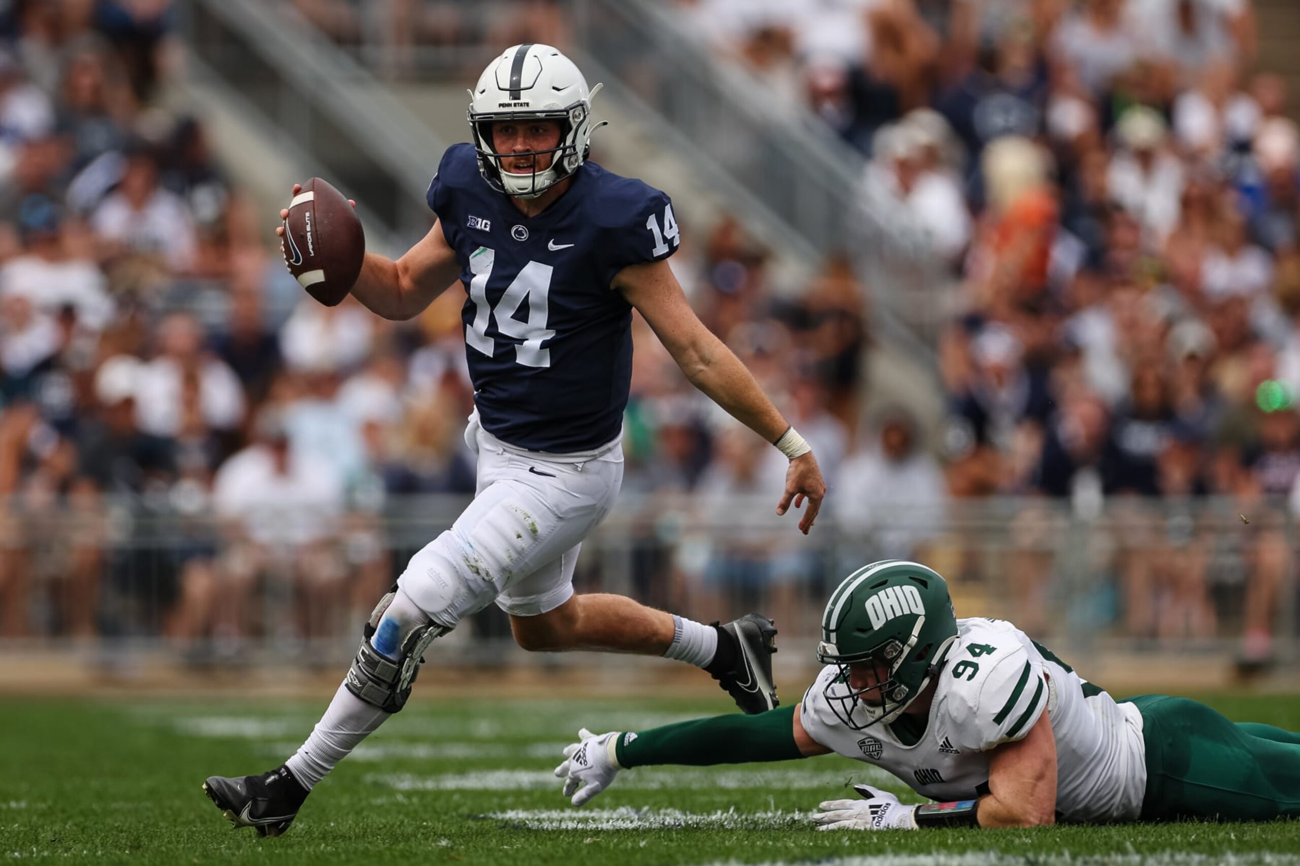 STATE COLLEGE, PA - SEPTEMBER 10: Sean Clifford #14 of the Penn State Nittany Lions scrambles to avoid the pressure of Bradley Weaver #94 of the Ohio Bobcats during the first half at Beaver Stadium on September 10, 2022 in State College, Pennsylvania. (Photo by Scott Taetsch/Getty Images)