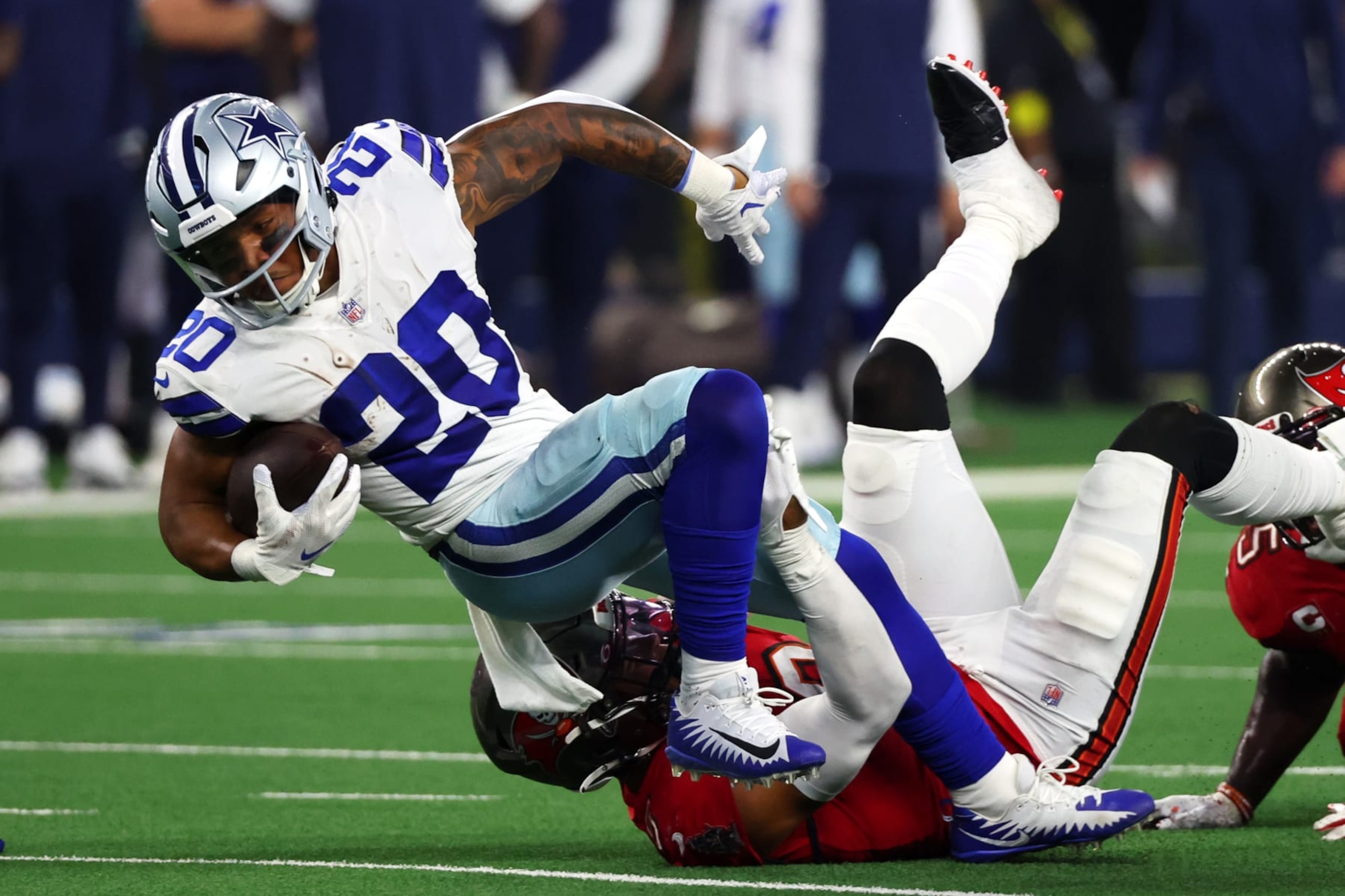 ARLINGTON, TEXAS - SEPTEMBER 11: Tony Pollard #20 of the Dallas Cowboys is tackled by Joe Tryon-Shoyinka #9 of the Tampa Bay Buccaneers during the second half at AT&T Stadium on September 11, 2022 in Arlington, Texas. (Photo by Richard Rodriguez/Getty Images)