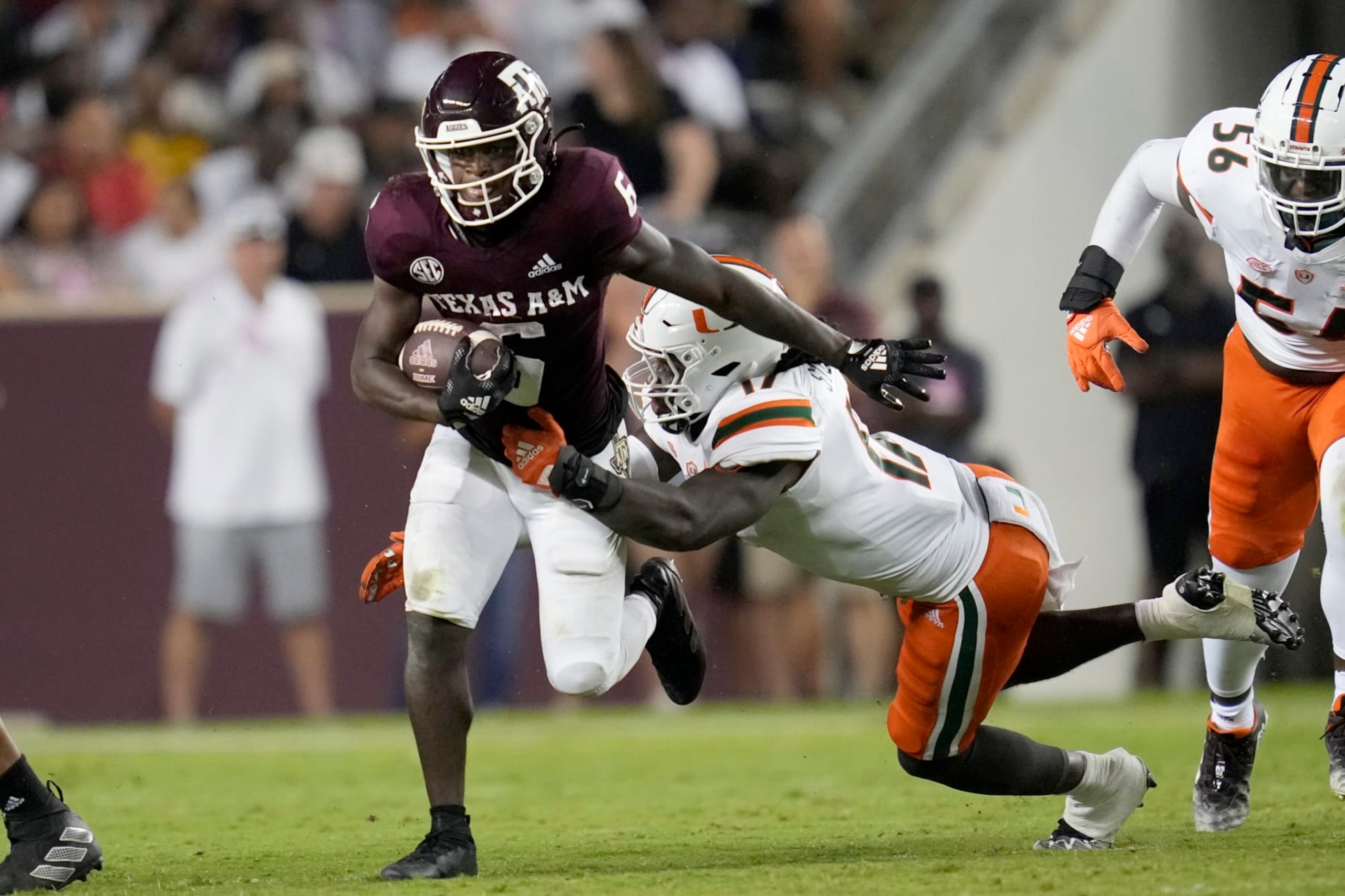 Texas A&M running back Devon Achane (6) breaks away from an attempted tackle by Miami linebacker Waynmon Steed Jr. (17) during the first half of an NCAA college football game Saturday, Sept. 17, 2022, in College Station, Texas. (AP Photo/Sam Craft)