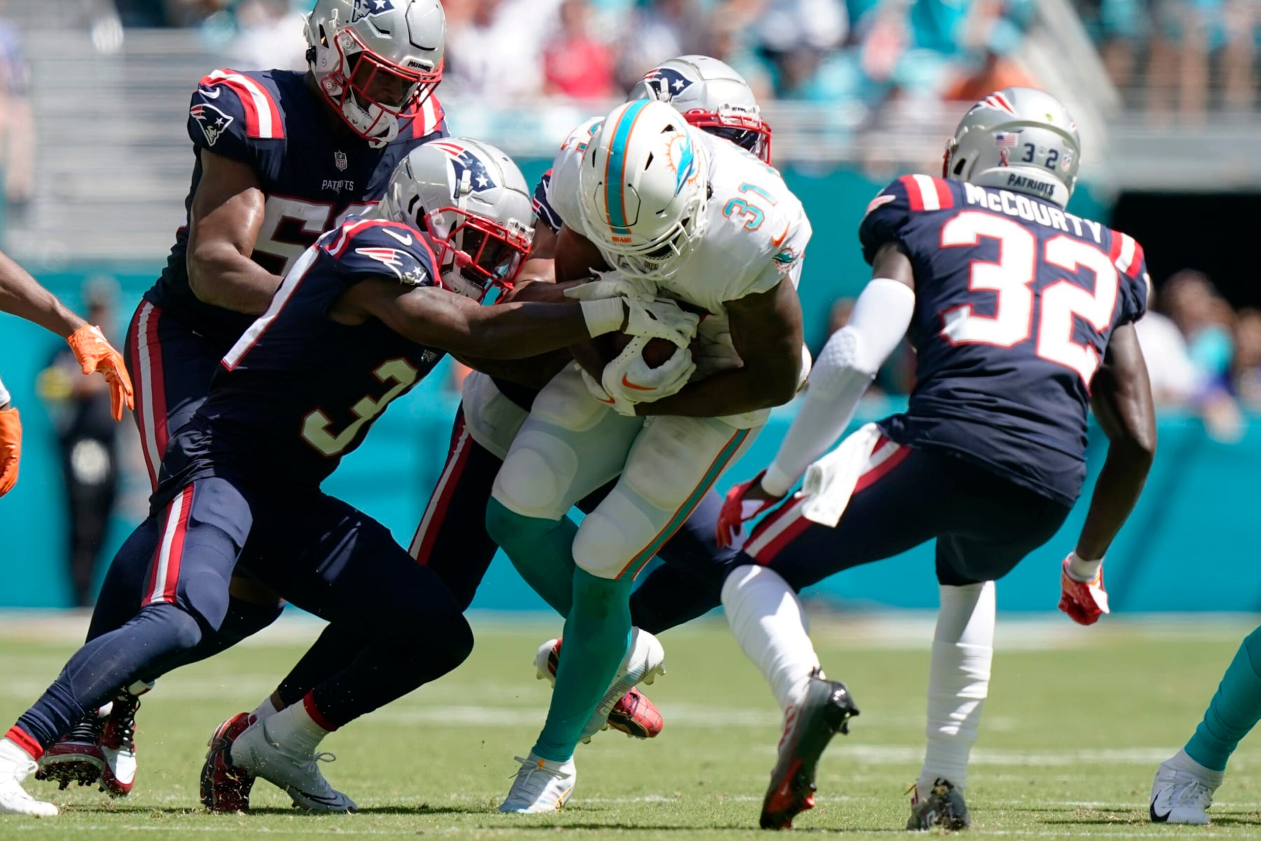 New England Patriots cornerback Jonathan Jones (31) tackles Miami Dolphins running back Raheem Mostert (31) during the second half of an NFL football game, Sunday, Sept. 11, 2022, in Miami Gardens, Fla. (AP Photo/Lynne Sladky)