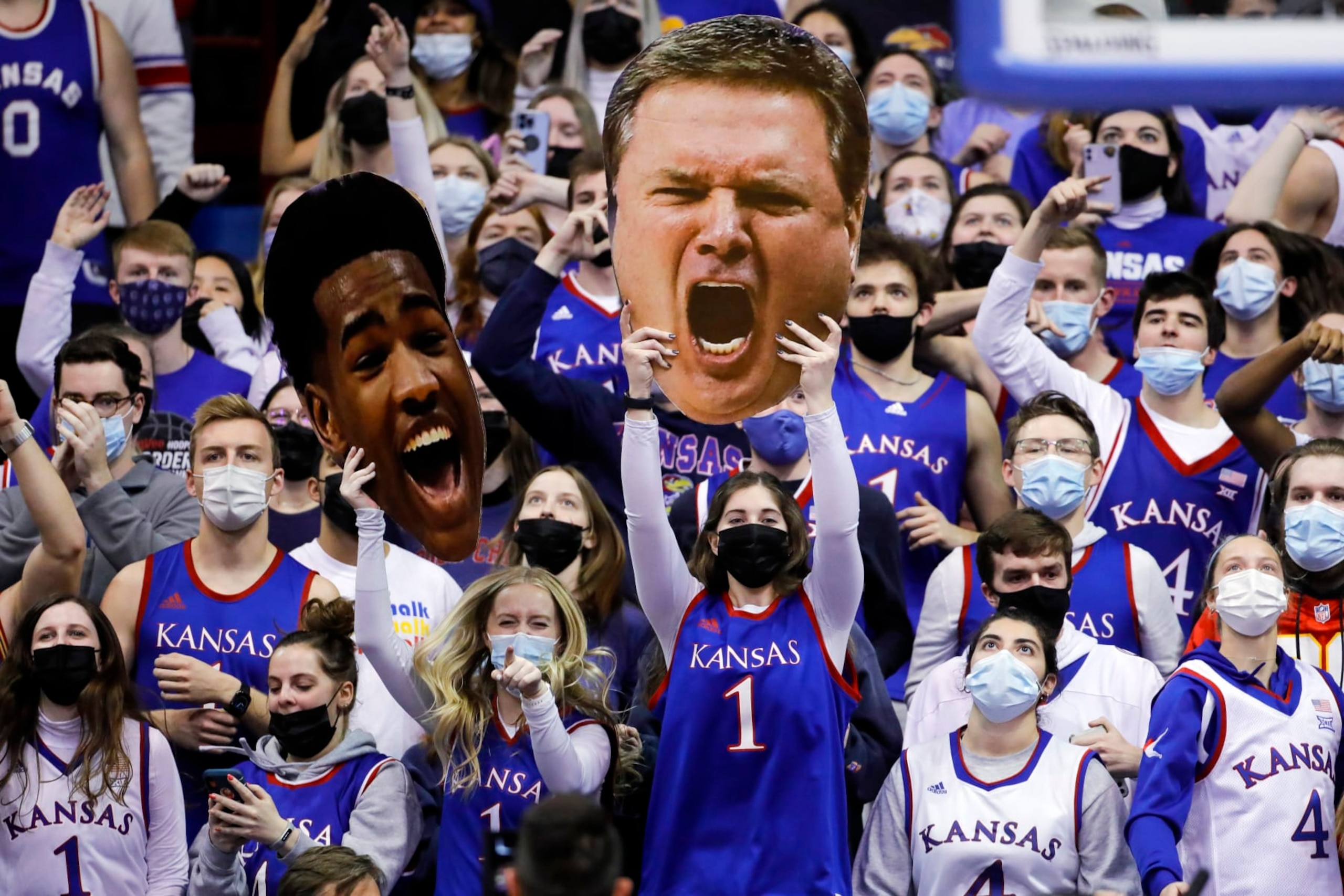 Masked Jayhawk fans hold photo heads of Kansas guard Ochai Agbaji and head coach Bill Self during an NCAA college basketball game against Texas Tech on Monday, Jan. 24, 2022 in Lawrence, Kan. (AP Photo/Colin E. Braley)