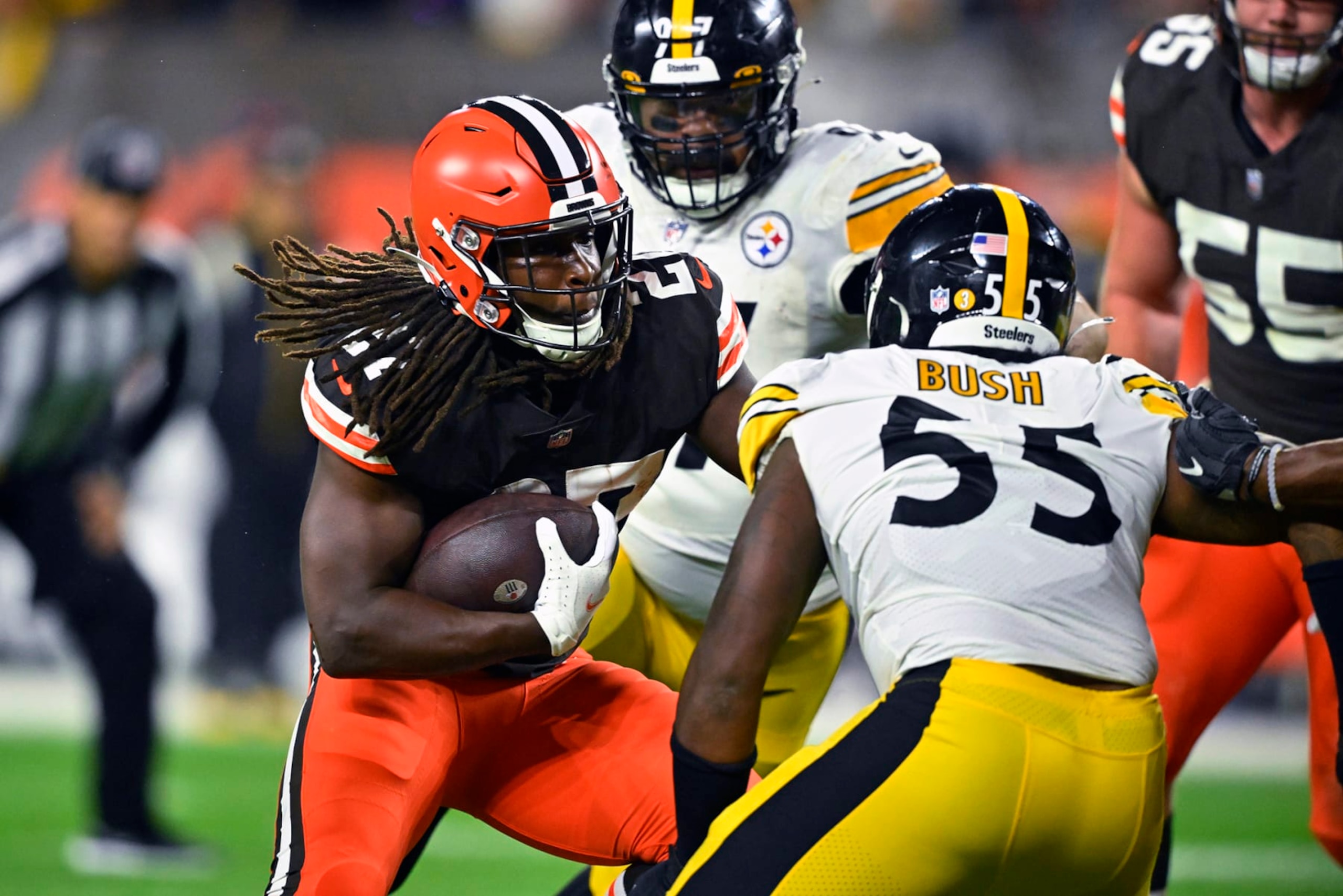 CORRECTS BROWNS PLAYER TO KAREEM HUNT, INSTEAD OF NICK CHUBB - Cleveland Browns running back Kareem Hunt (27) runs between Pittsburgh Steelers' Cameron Heyward (97) and Devin Bush (55) during the first half of an NFL football game in Cleveland, Thursday, Sept. 22, 2022. (AP Photo/David Richard)