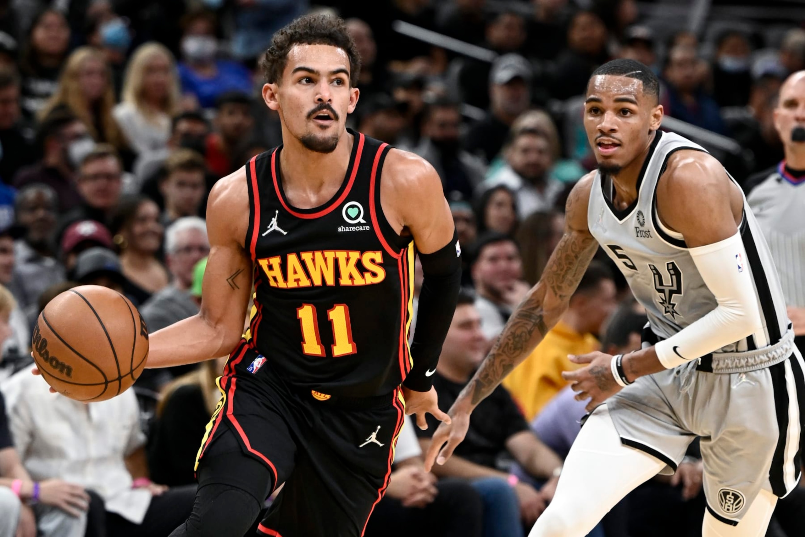 Atlanta Hawks' Trae Young (11) drives past San Antonio Spurs' Dejounte Murray during the first half of an NBA basketball game, Wednesday, Nov. 24, 2021, in San Antonio. (AP Photo/Darren Abate)