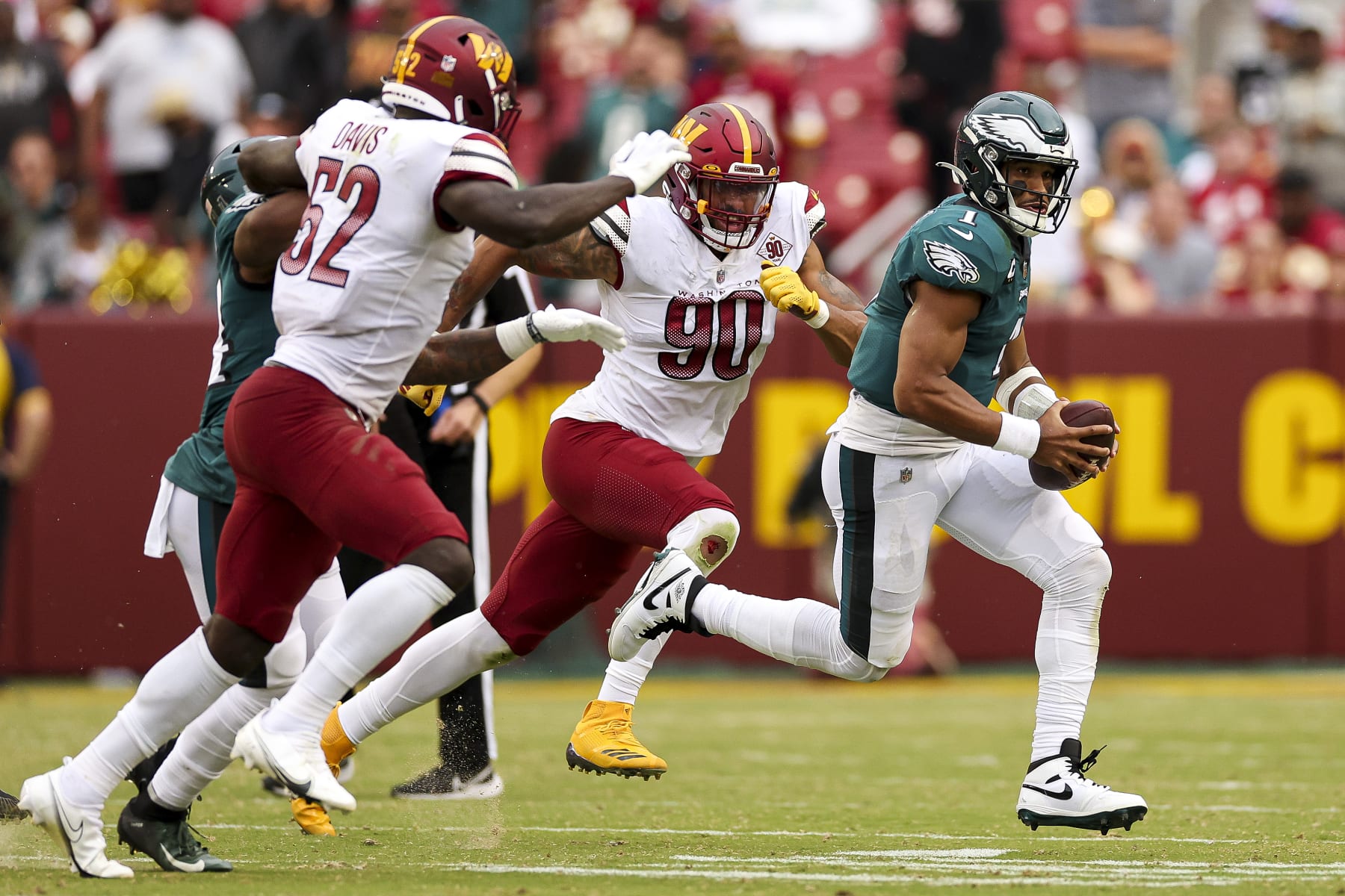 LANDOVER, MARYLAND - SEPTEMBER 25: Quarterback Jalen Hurts #1 of the Philadelphia Eagles runs past linebacker Jamin Davis #52 of the Washington Commanders and defensive end Montez Sweat #90 of the Washington Commanders during the second half at FedExField on September 25, 2022 in Landover, Maryland. (Photo by Patrick Smith/Getty Images)