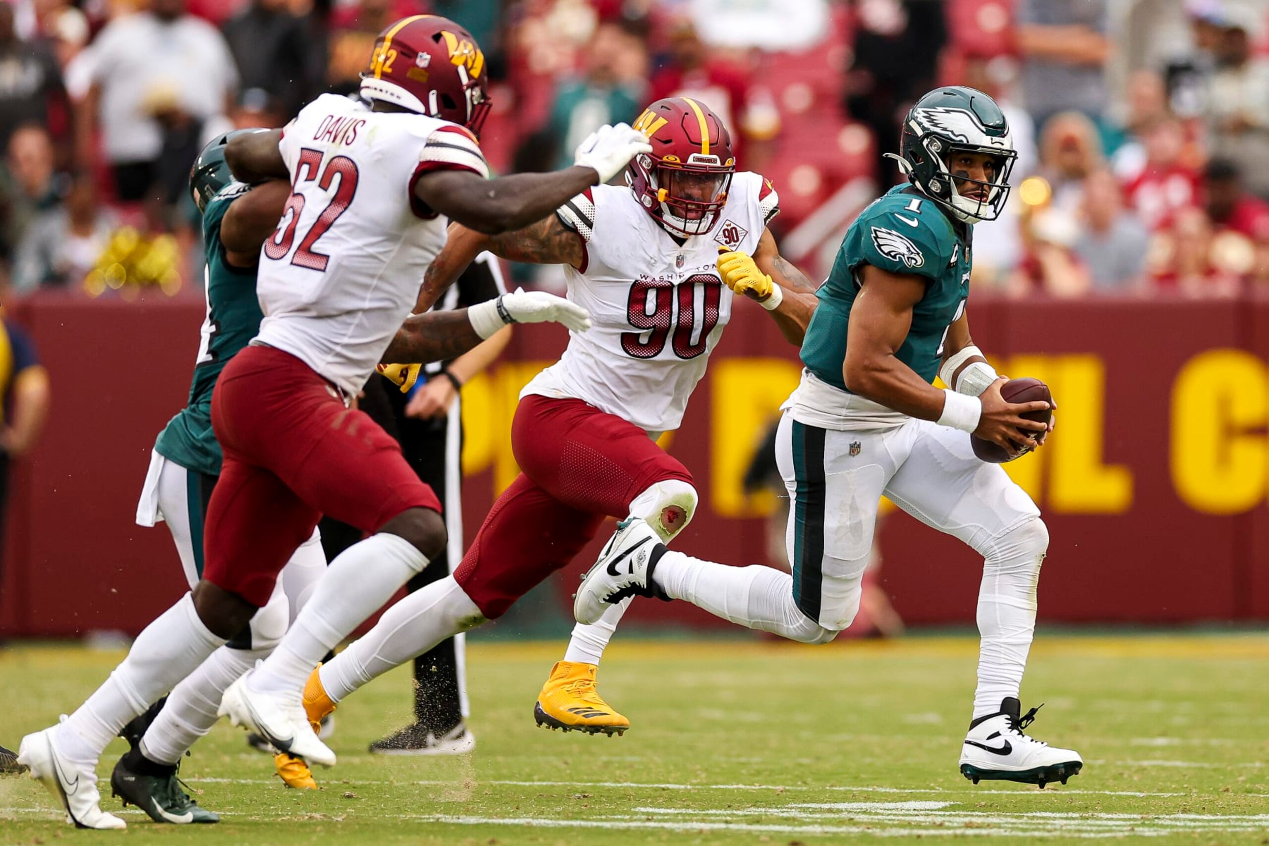 LANDOVER, MARYLAND - SEPTEMBER 25: Quarterback Jalen Hurts #1 of the Philadelphia Eagles runs past linebacker Jamin Davis #52 of the Washington Commanders and defensive end Montez Sweat #90 of the Washington Commanders during the second half at FedExField on September 25, 2022 in Landover, Maryland. (Photo by Patrick Smith/Getty Images)