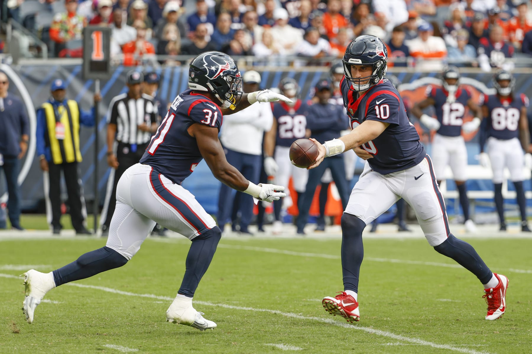 Houston Texans quarterback Davis Mills (10) passes the ball to running back Dameon Pierce (31) during the second half of an NFL football game against the Chicago Bears, Sunday, Sept. 25, 2022, in Chicago. (AP Photo/Kamil Krzaczynski)