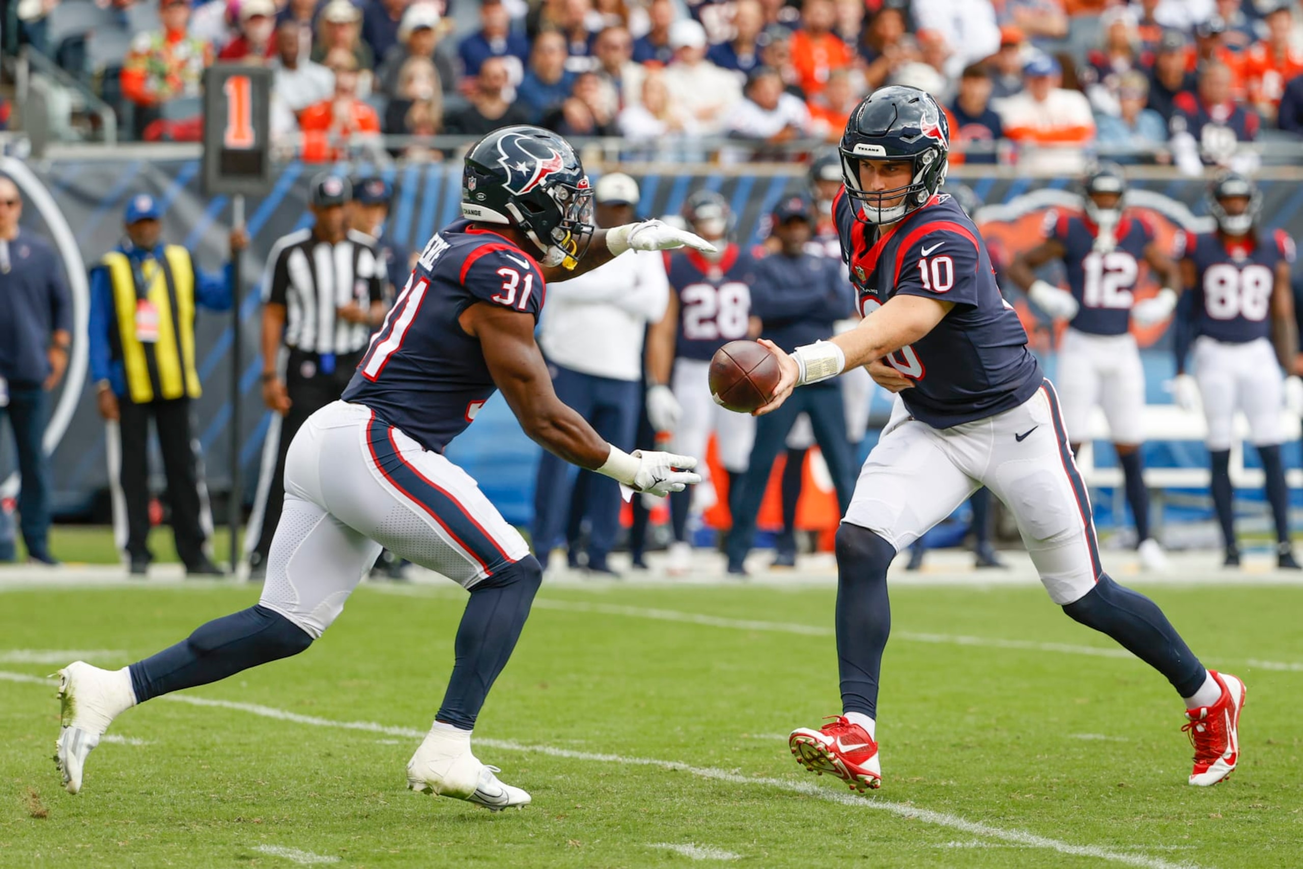 Houston Texans quarterback Davis Mills (10) passes the ball to running back Dameon Pierce (31) during the second half of an NFL football game against the Chicago Bears, Sunday, Sept. 25, 2022, in Chicago. (AP Photo/Kamil Krzaczynski)