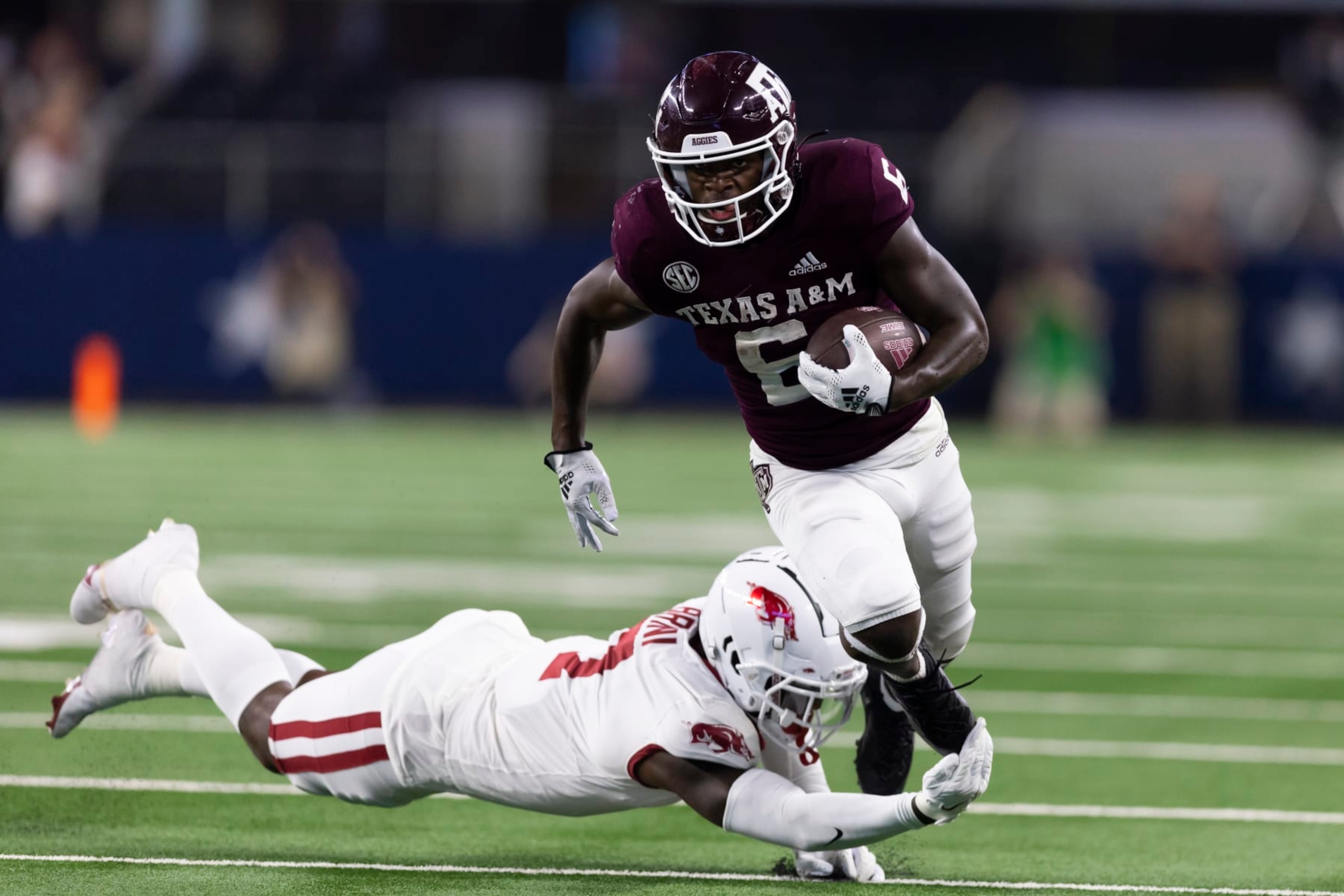 Arkansas defensive back Latavious Brini (7) trips Texas A&M running back Devon Achane (6) during the second half of an NCAA college football game Saturday, Sept. 24, 2022, in Arlington, Texas. Texas A&M won 23-21. (AP Photo/Brandon Wade)