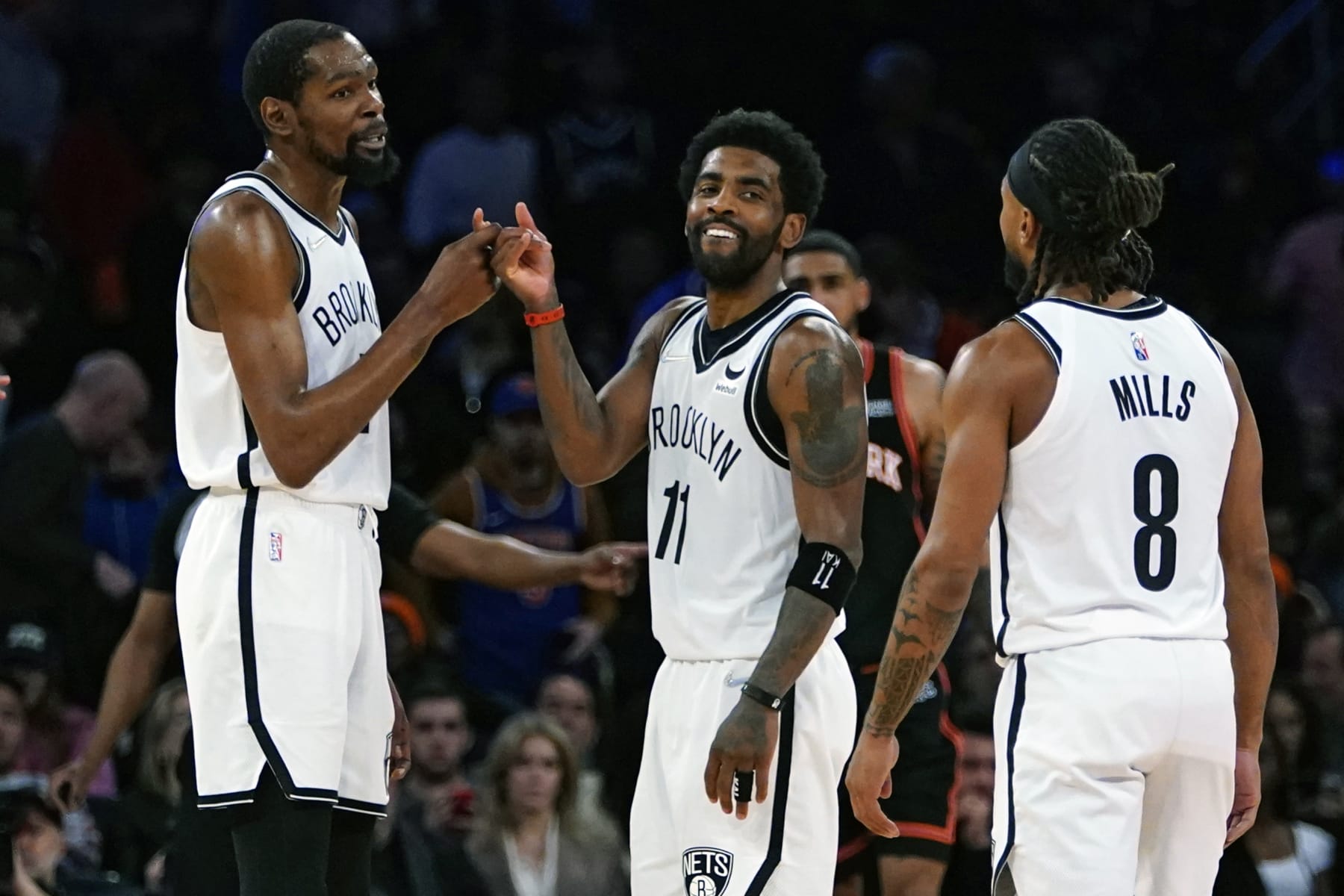 Brooklyn Nets' Kevin Durant, left, and Kyrie Irving (11) celebrate with Patty Mills (8) during the second half of an NBA basketball game against the New York Knicks Wednesday, April 6, 2022, in New York. The Nets won 110-98. (AP Photo/Frank Franklin II)