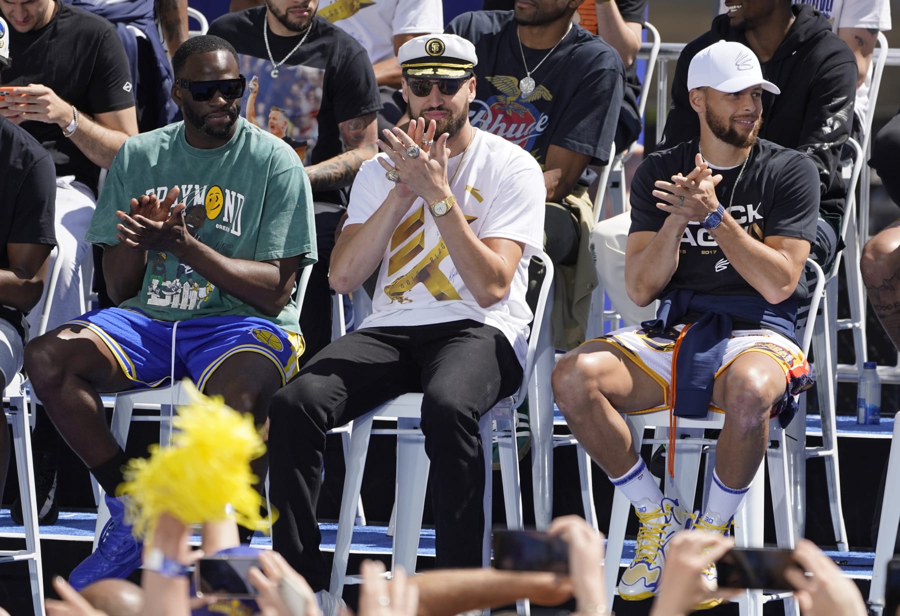 From left, Golden State Warriors' Draymond Green, Klay Thompson and Stephen Curry clap on stage before the start of their NBA championship parade in San Francisco, Monday, June 20, 2022. (AP Photo/Eric Risberg)