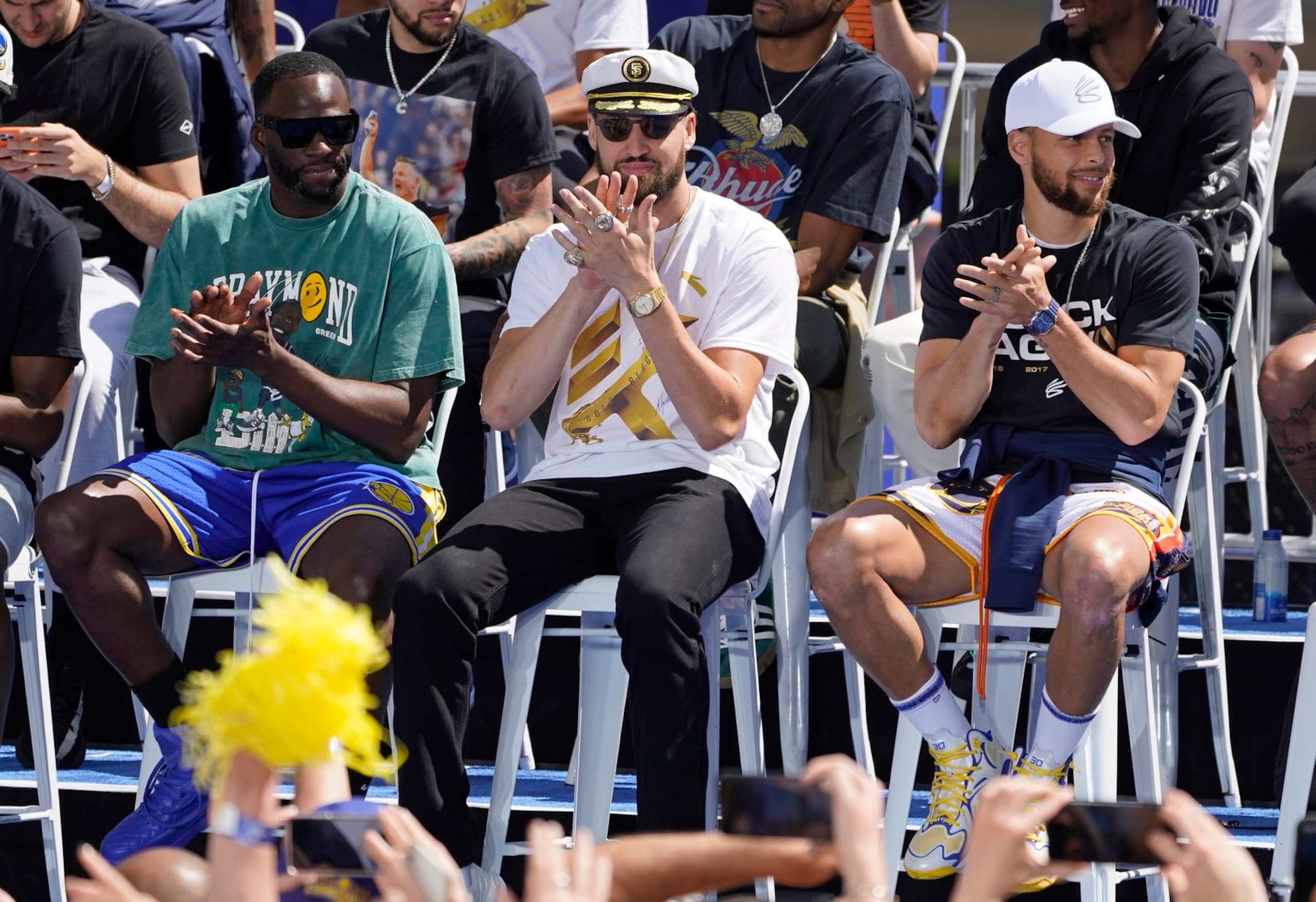 From left, Golden State Warriors' Draymond Green, Klay Thompson and Stephen Curry clap on stage before the start of their NBA championship parade in San Francisco, Monday, June 20, 2022. (AP Photo/Eric Risberg)