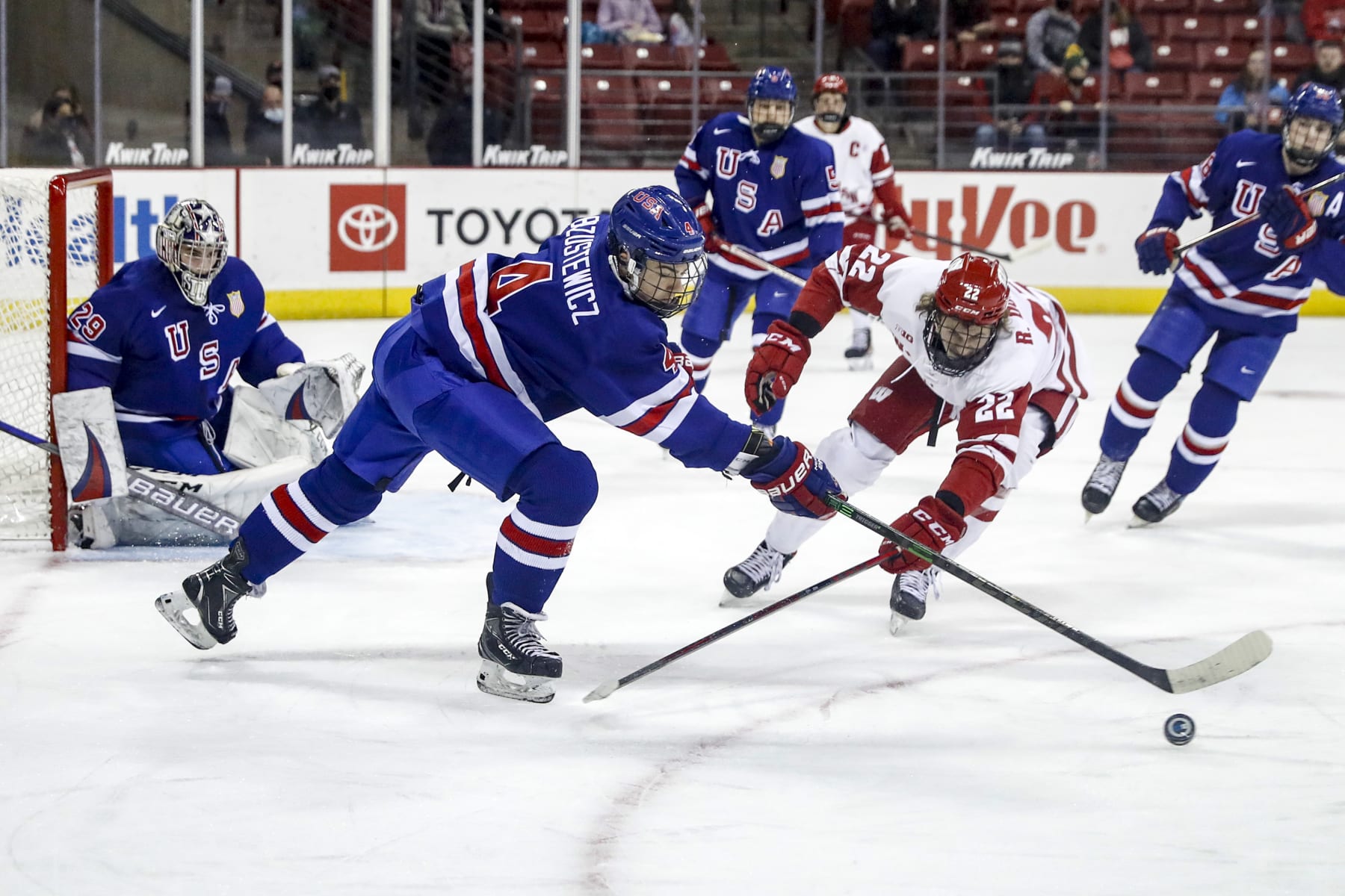MADISON, WI - DECEMBER 02: Wisconsin forward Ryder Donovan (22) and U-18 defenseman Hunter Brzustewicz (4) battle for the puck while U-18 goalie Dylan Silverstein (29) looks on during a college hockey match between the University of Wisconsin Badgers and the U.S. National Under-18 Team on December 2, 2021 at the Kohl Center in Madison, WI. (Photo by Lawrence Iles/Icon Sportswire via Getty Images)