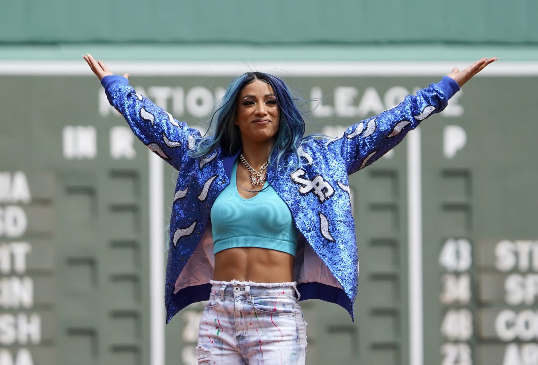 WWE wrestler Sasha Banks reacts before throwing out the first pitch before the start of baseball game between the Boston Red Sox and the Chicago White Sox at Fenway Park, Sunday, May 8, 2022, in Boston. (AP Photo/Mary Schwalm)