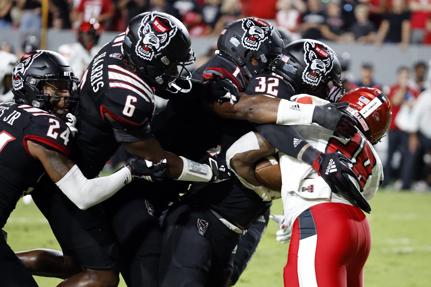 Texas Tech's Tahj Brooks (28) is stopped by North Carolina State's Drake Thomas (32), Isaiah Moore (1), Jakeen Harris (6), and Derrek Pitts Jr. (24) during the first half of an NCAA college football game in Raleigh, N.C., Saturday, Sept. 17, 2022. (AP Photo/Karl B DeBlaker)
