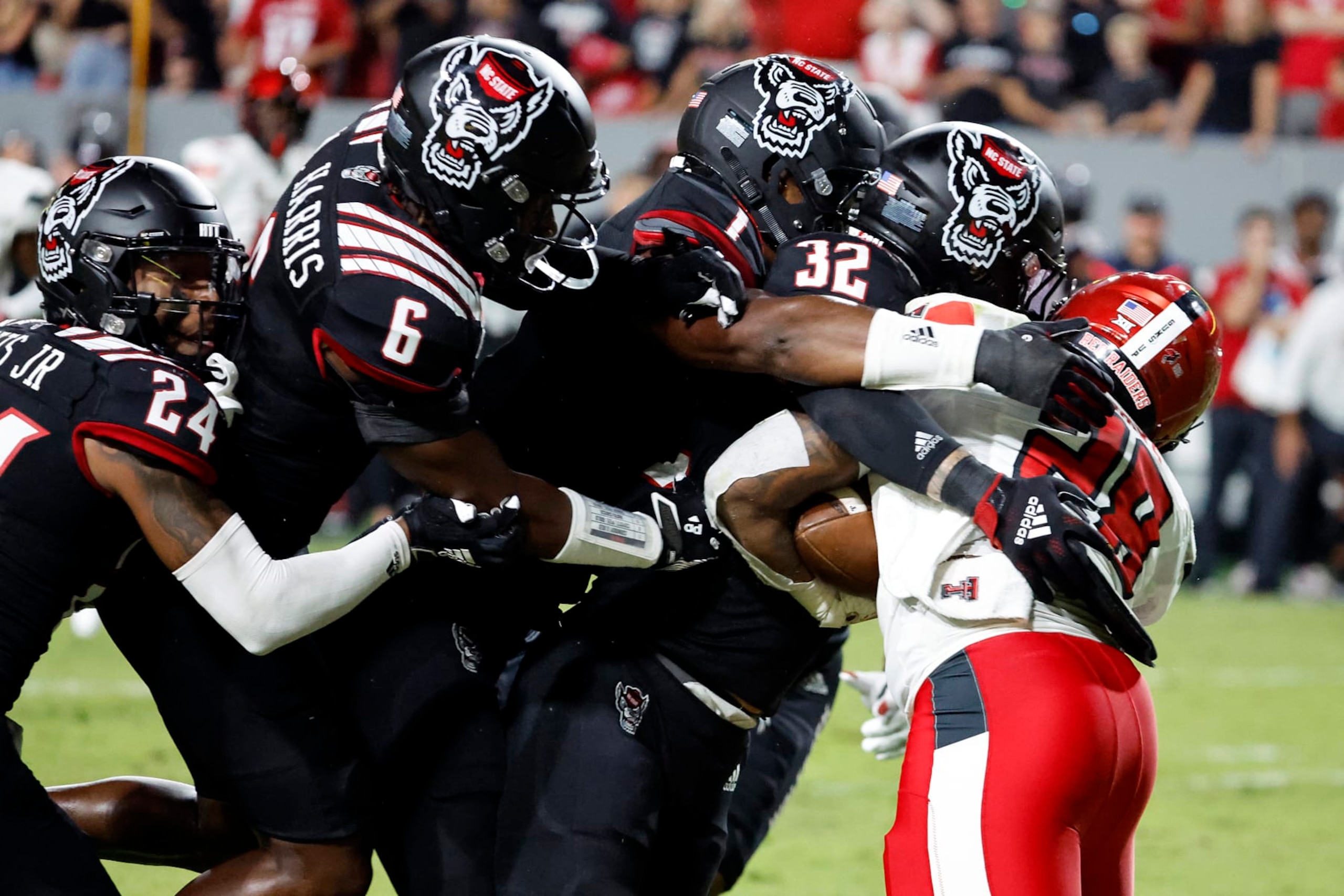 Texas Tech's Tahj Brooks (28) is stopped by North Carolina State's Drake Thomas (32), Isaiah Moore (1), Jakeen Harris (6), and Derrek Pitts Jr. (24) during the first half of an NCAA college football game in Raleigh, N.C., Saturday, Sept. 17, 2022. (AP Photo/Karl B DeBlaker)